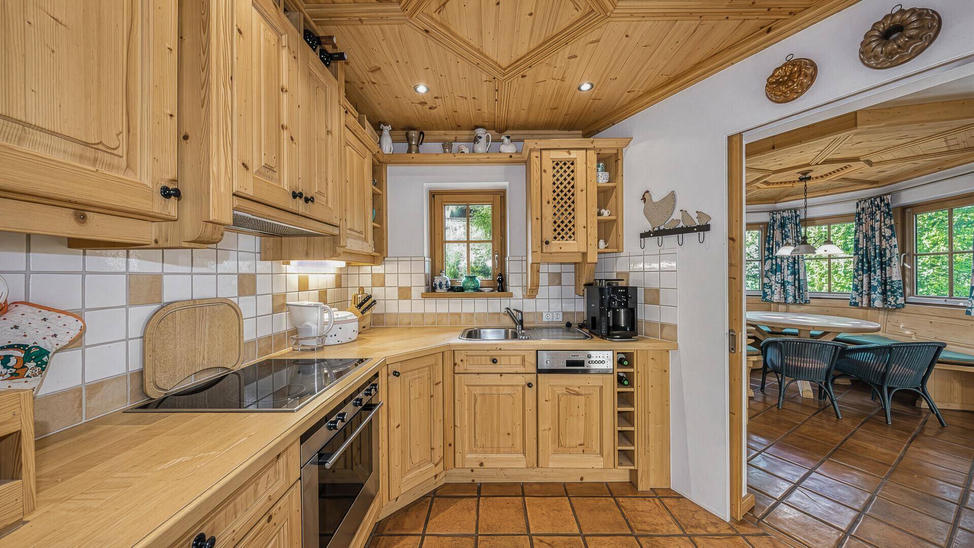 Traditionelle Holzküche mit Fliesenboden, Einbaugeräten und Blick in die Essecke.