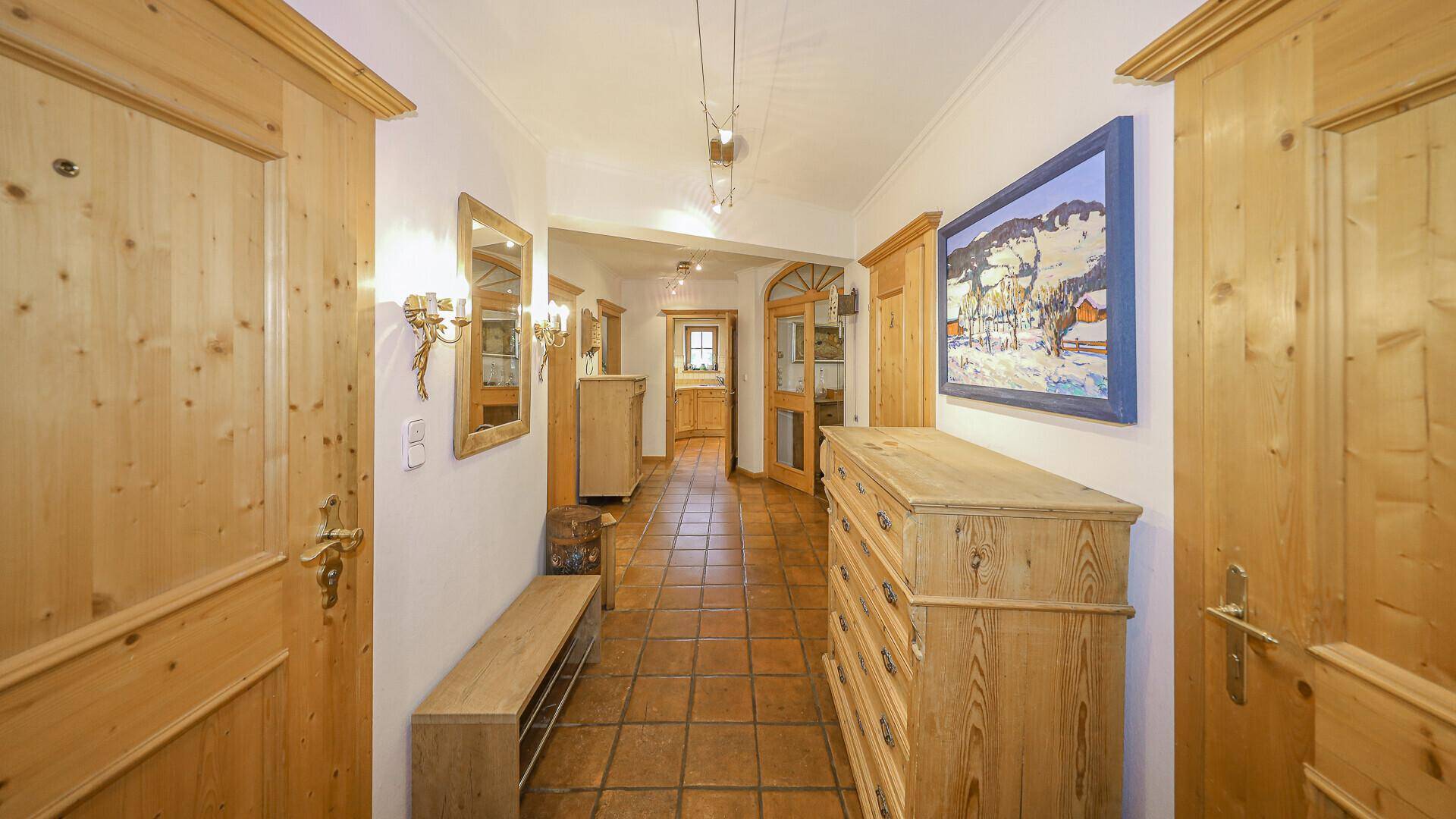 Geräumiger Flur mit Terrakottafliesen, Holzmöbeln und traditioneller Dekoration.