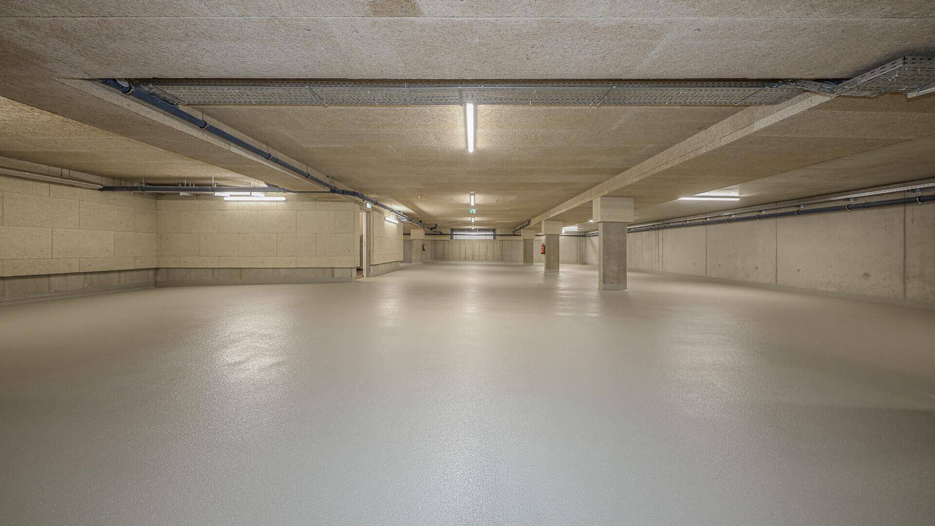 Geräumige, leere Tiefgarage mit Betonwänden und Beleuchtung.