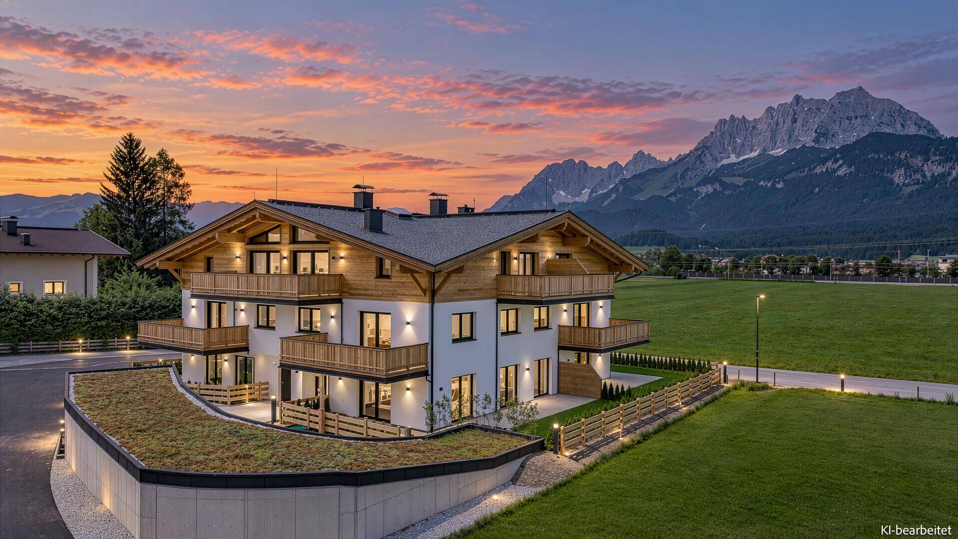 Modernes Wohngebäude mit Gründach und Bergblick bei Sonnenuntergang.