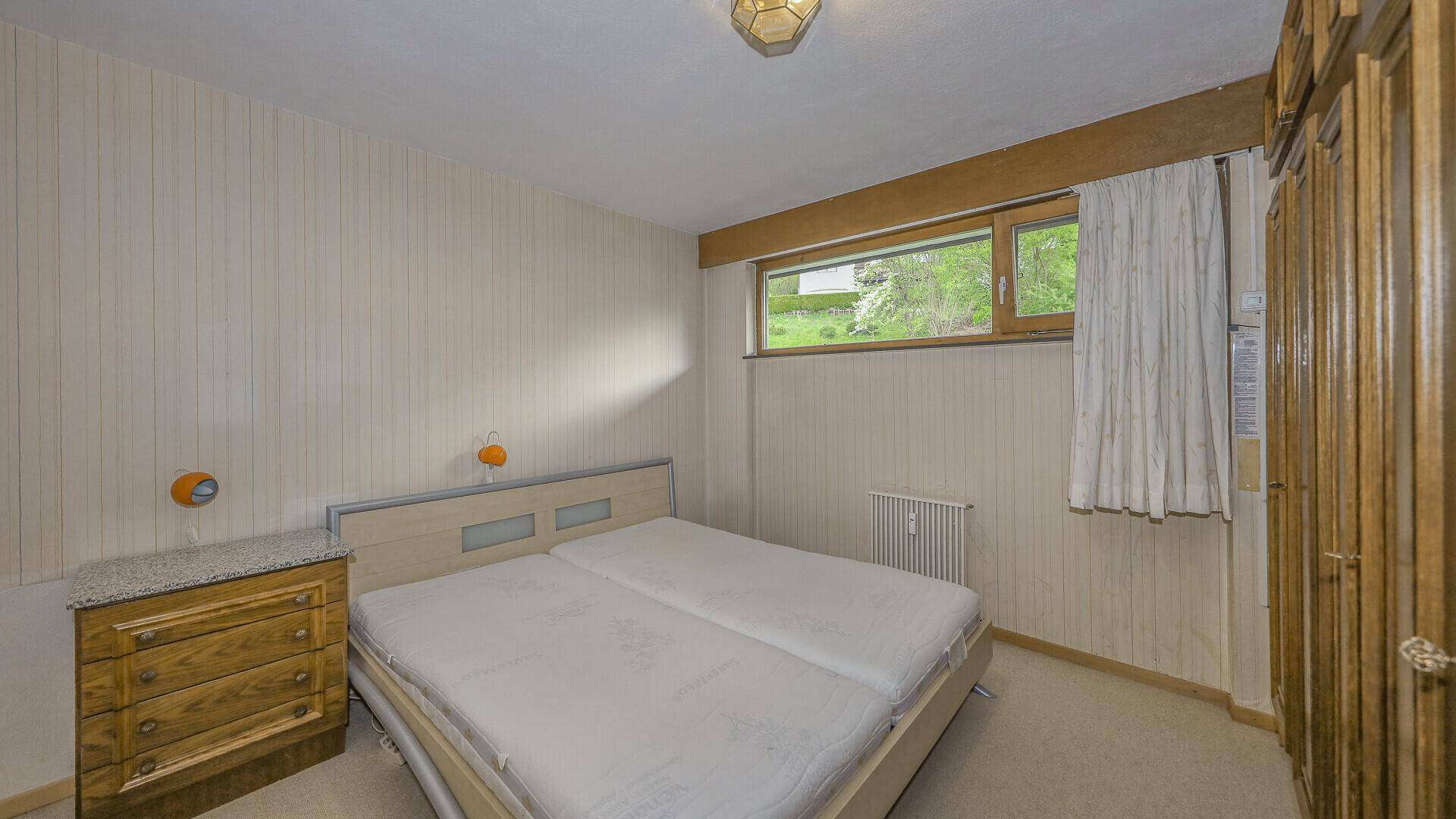 Gemütliches Schlafzimmer mit Doppelbett, Holzmöbeln und Fensterblick ins Grüne.