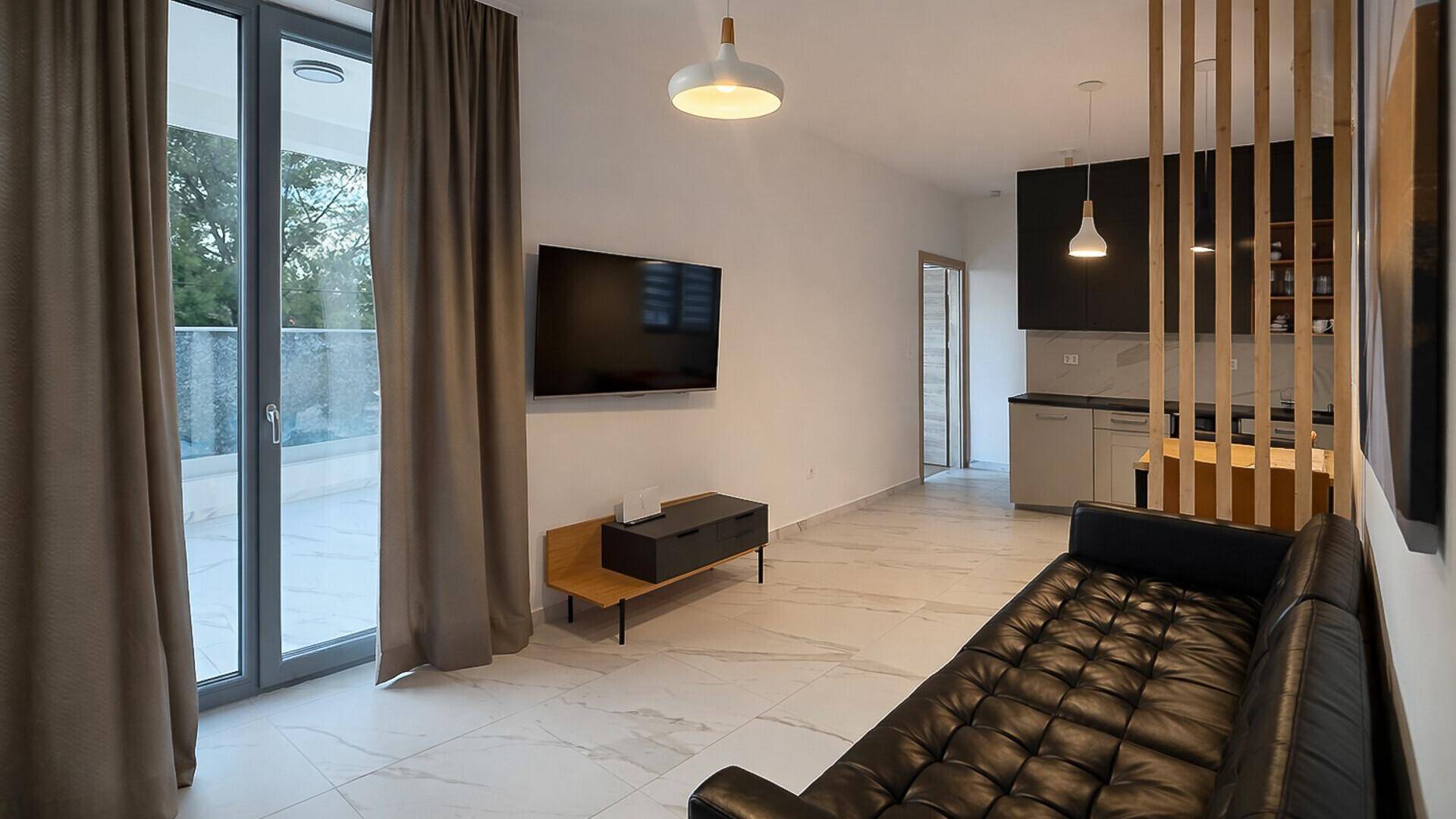 Heller Wohnbereich mit modernen Fliesen, bequemer Couch und Zugang zur Terrasse.