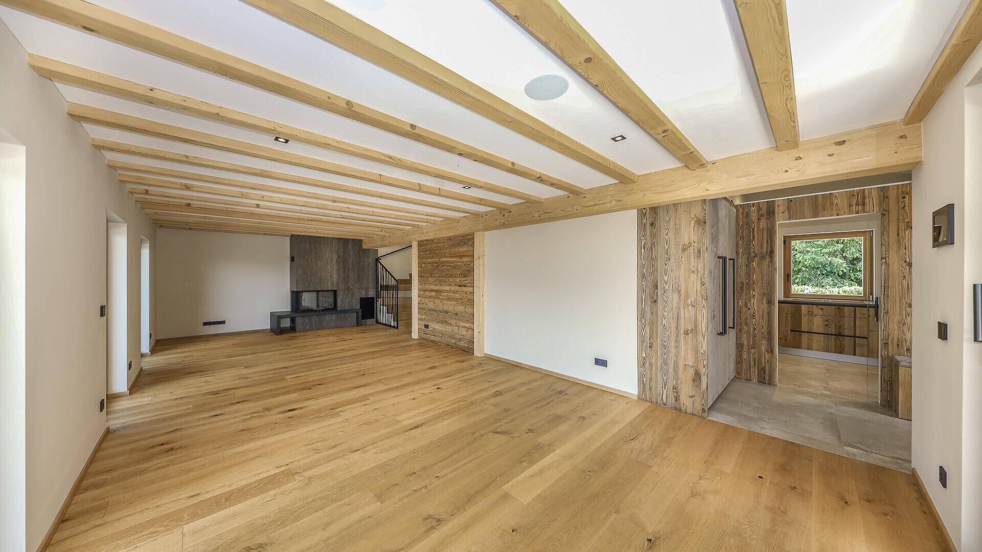 Offener Wohnbereich mit Holzbalkendecke, Eichenparkett und Holzwänden im alpinen Stil.