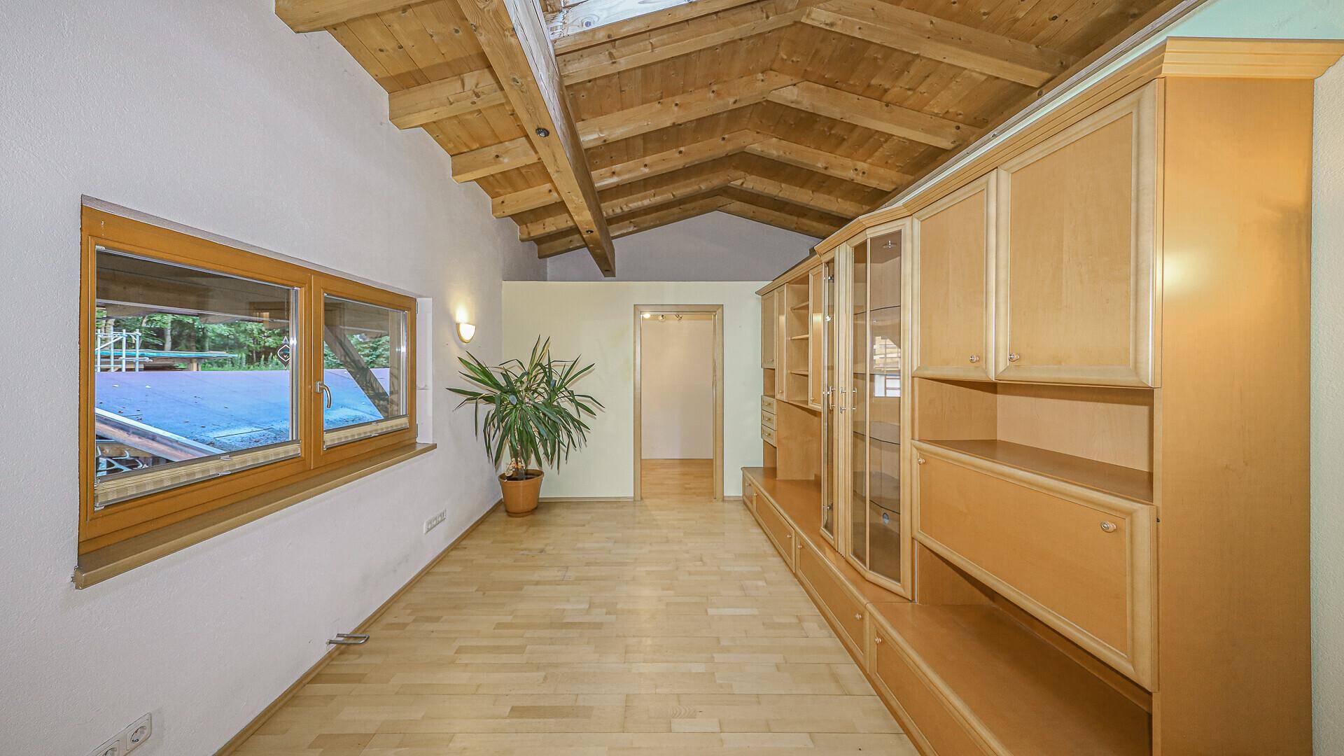 Heller Wohnbereich mit Holzbalkendecke, Dachfenster und Einbauschränken, bietet viel Stauraum.