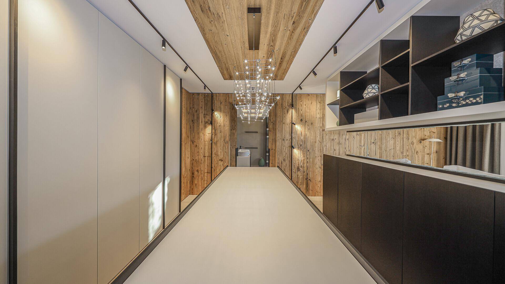 Langer Flur mit Holzwänden, Einbauschränken und moderner Deckenbeleuchtung.