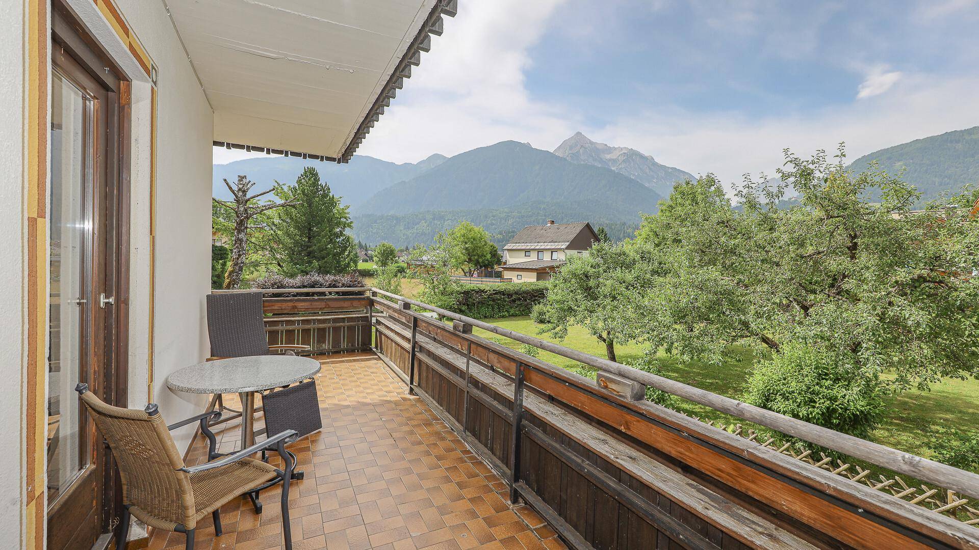 Balkon von Apartment 02 mit Fliesenboden, Holzgeländer und Sitzgelegenheiten, bietet einen schönen Bergblick.