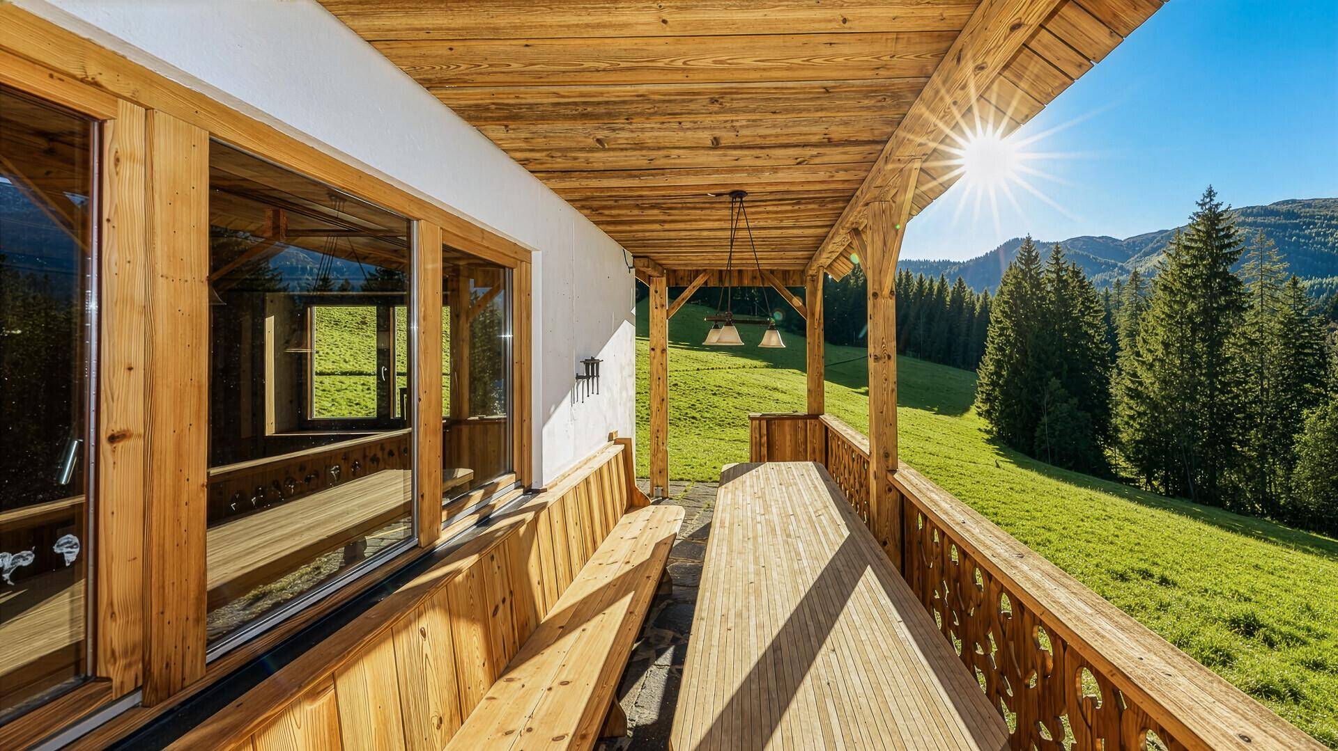 Sonnige Holzterrasse mit Sitzgelegenheiten und weitem Blick über die grüne Landschaft.