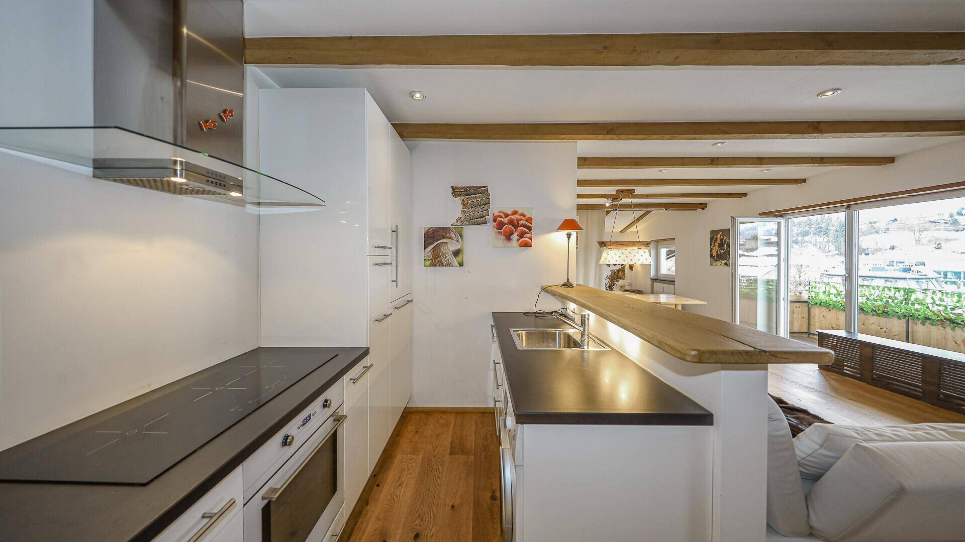 Funktionale Küche mit Induktionskochfeld, Backofen und Frühstücksbar, offen zum Wohnbereich.