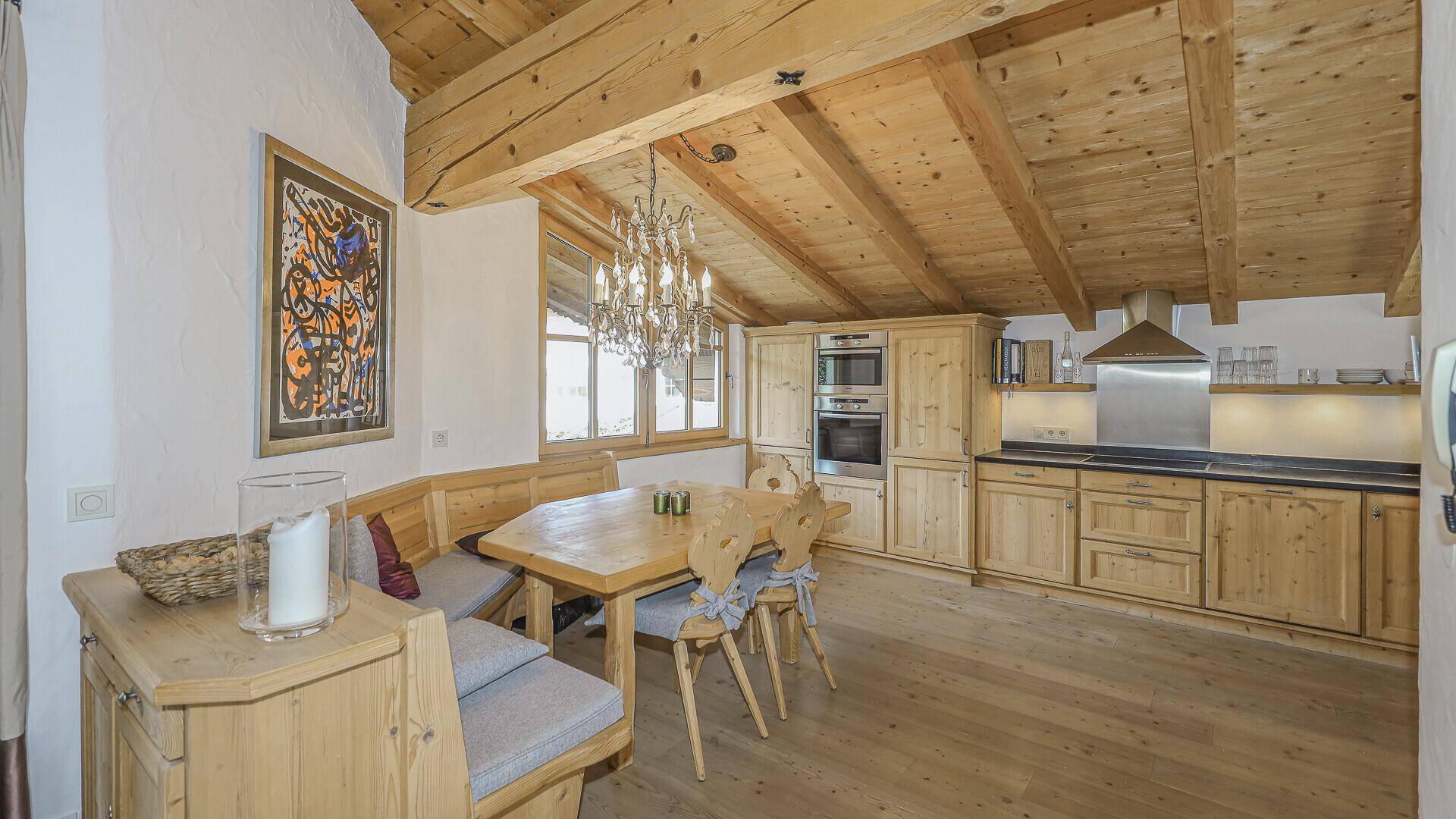 Traditionelle Holzküche mit Essbereich und modernen Einbaugeräten unter Holzbalkendecke.