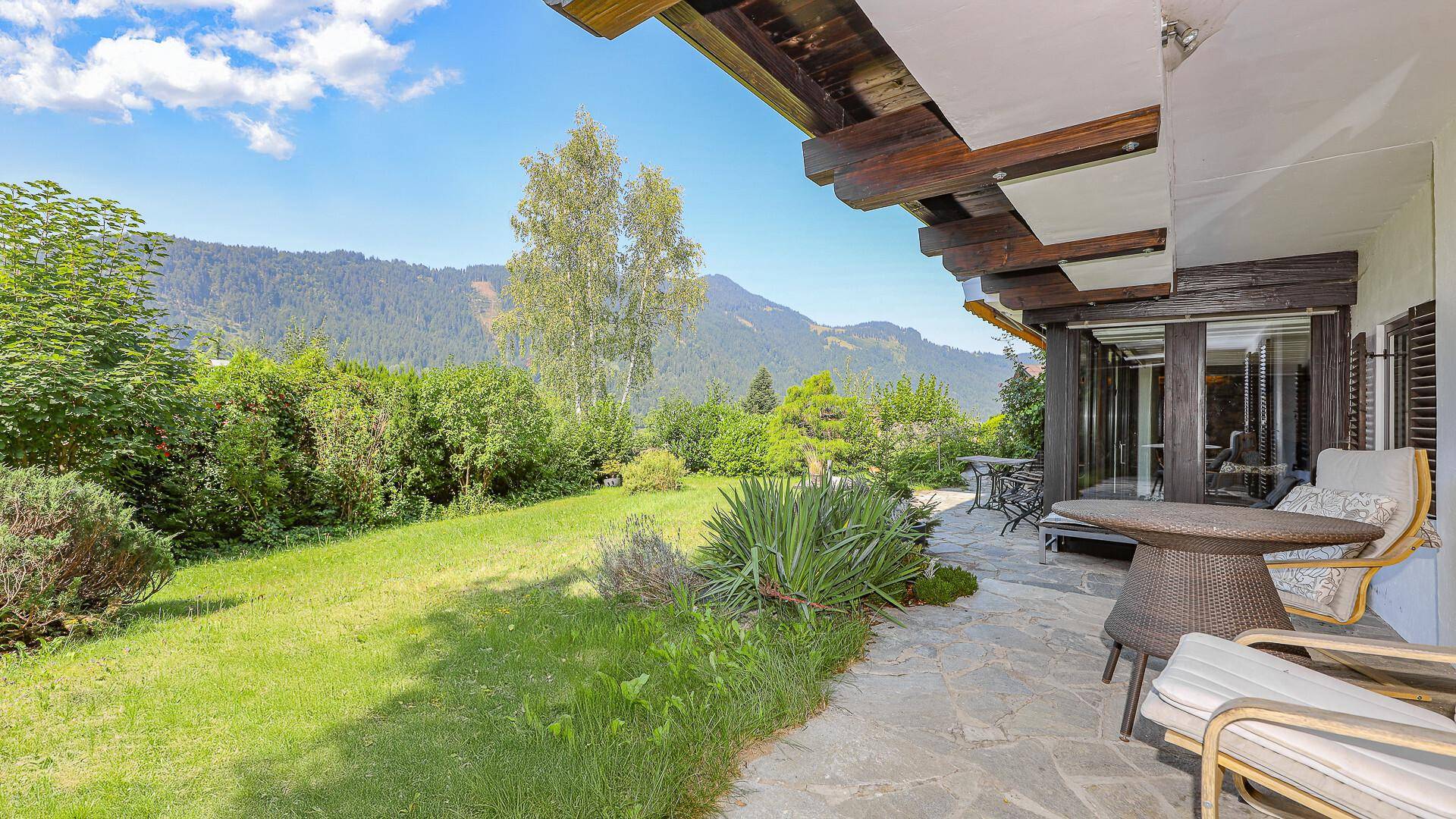 Gemütliche Terrasse mit Sitzgelegenheiten und angrenzendem Gartenbereich mit Bergblick.