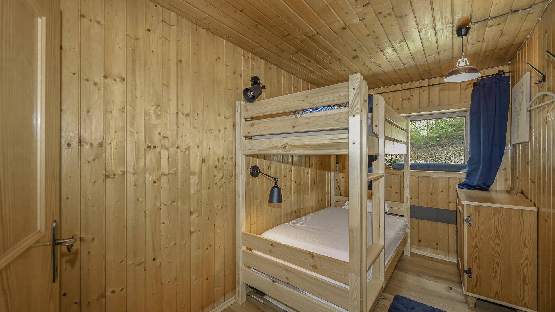 Kinderzimmer mit stabilem Holz-Etagenbett und Holztäfelung, ideal für Gäste oder Familien.