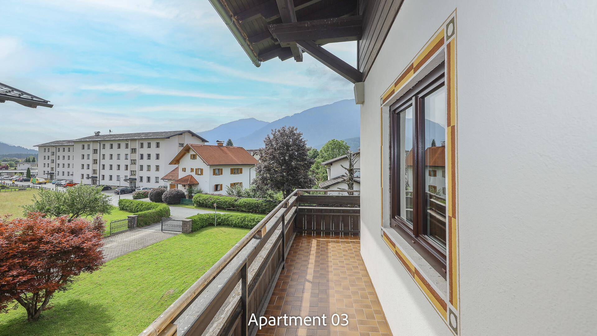Balkon von Apartment 03 mit Fliesenboden und Holzgeländer, bietet einen weiten Blick auf die Berglandschaft.