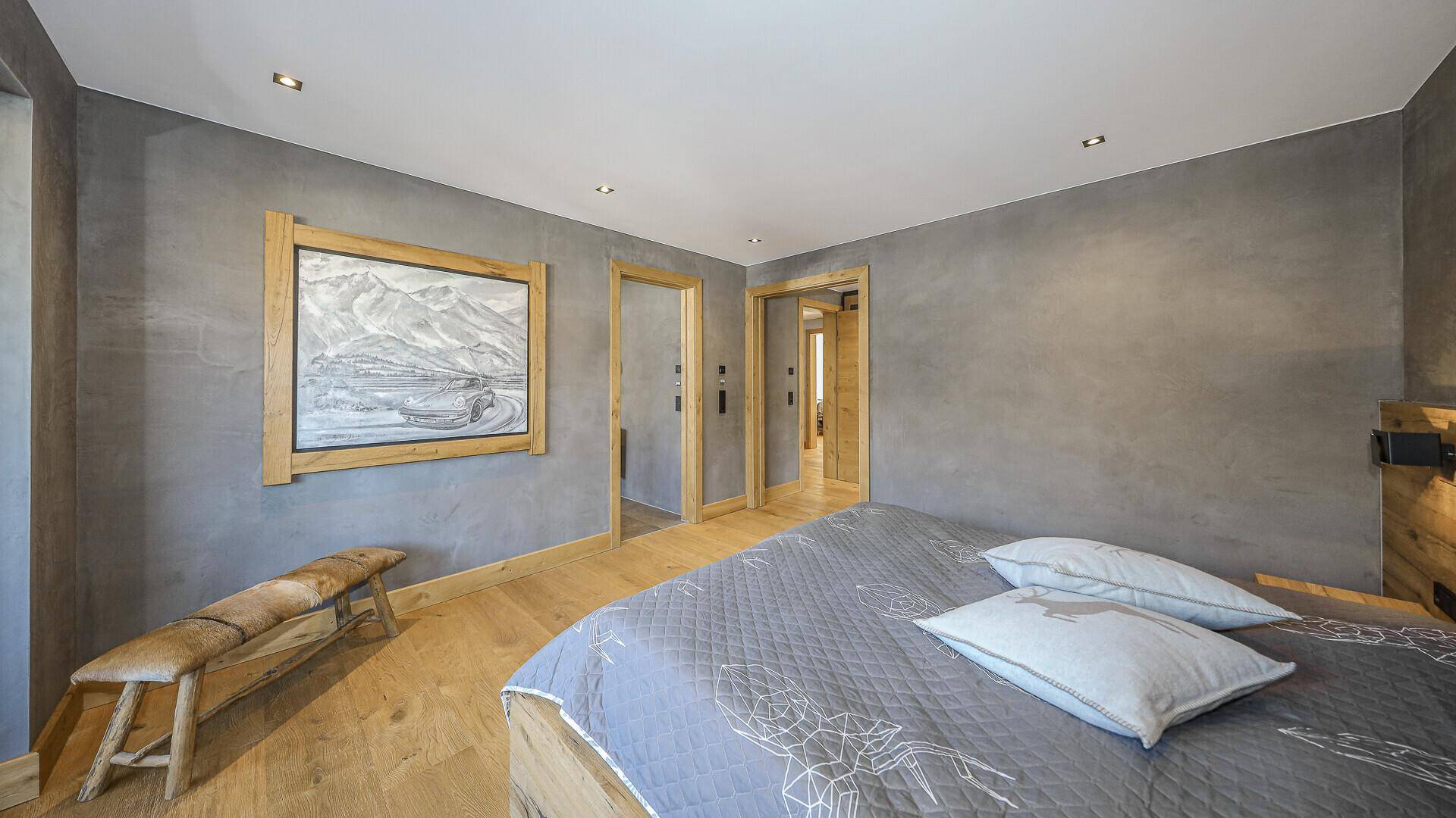 Schlafzimmer mit Holzboden, grauen Wänden und rustikaler Holzdekoration.