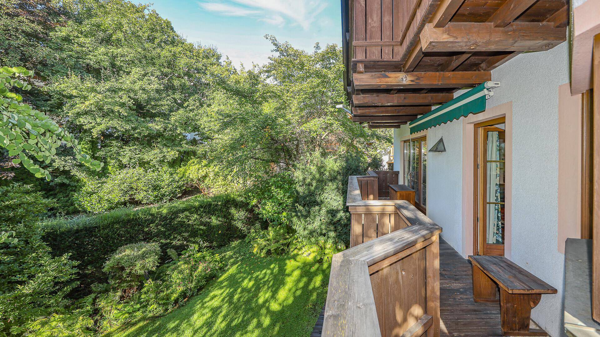 Langer Holzbalkon mit üppigem Grünblick und traditioneller Holzbrüstung.