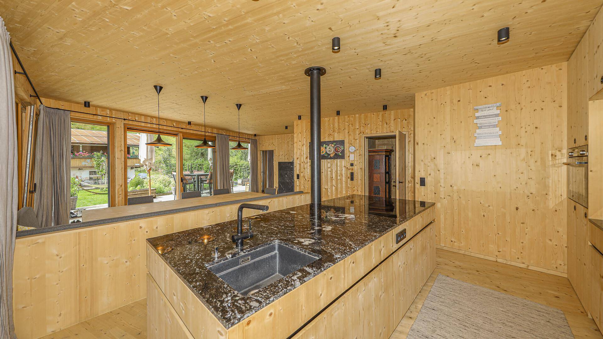 Moderne Küche mit Holzfronten, dunkler Granit-Arbeitsplatte und integrierter Spüle.