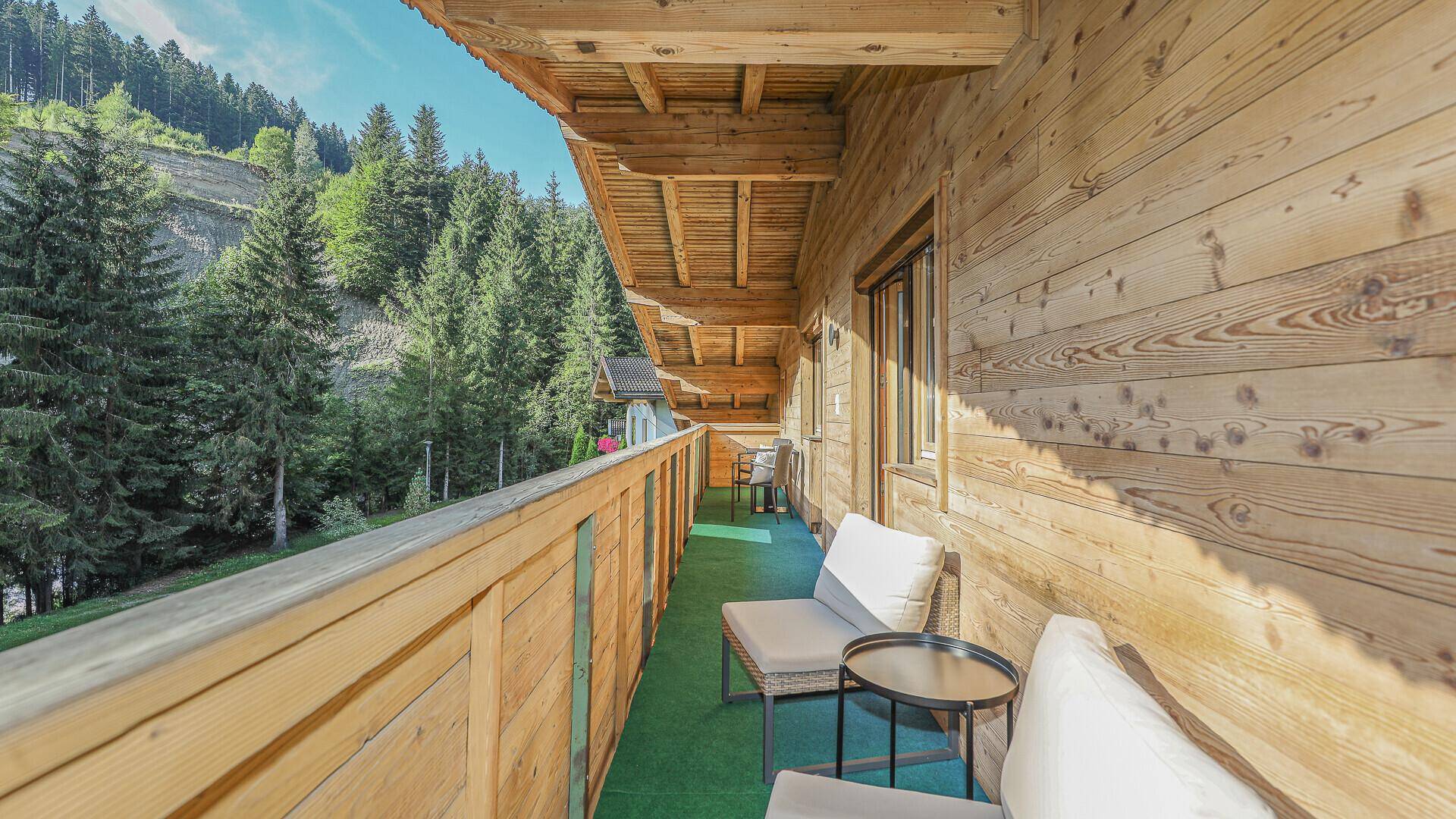 Langer Holzbalkon mit bequemen Sitzgelegenheiten und einem schönen Blick auf die umliegende Berglandschaft.
