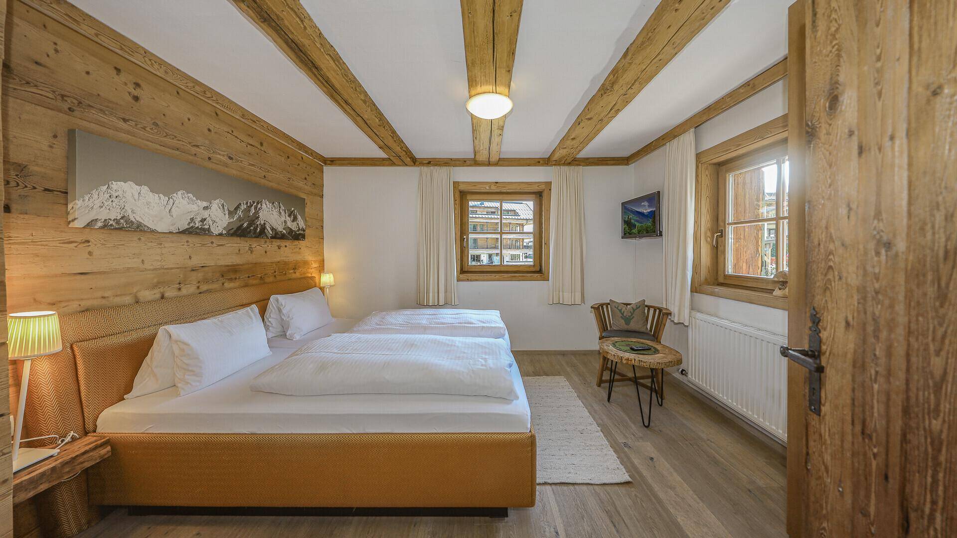 Geräumiges Schlafzimmer mit Doppelbett, Holzbalken und Blick auf die Umgebung.