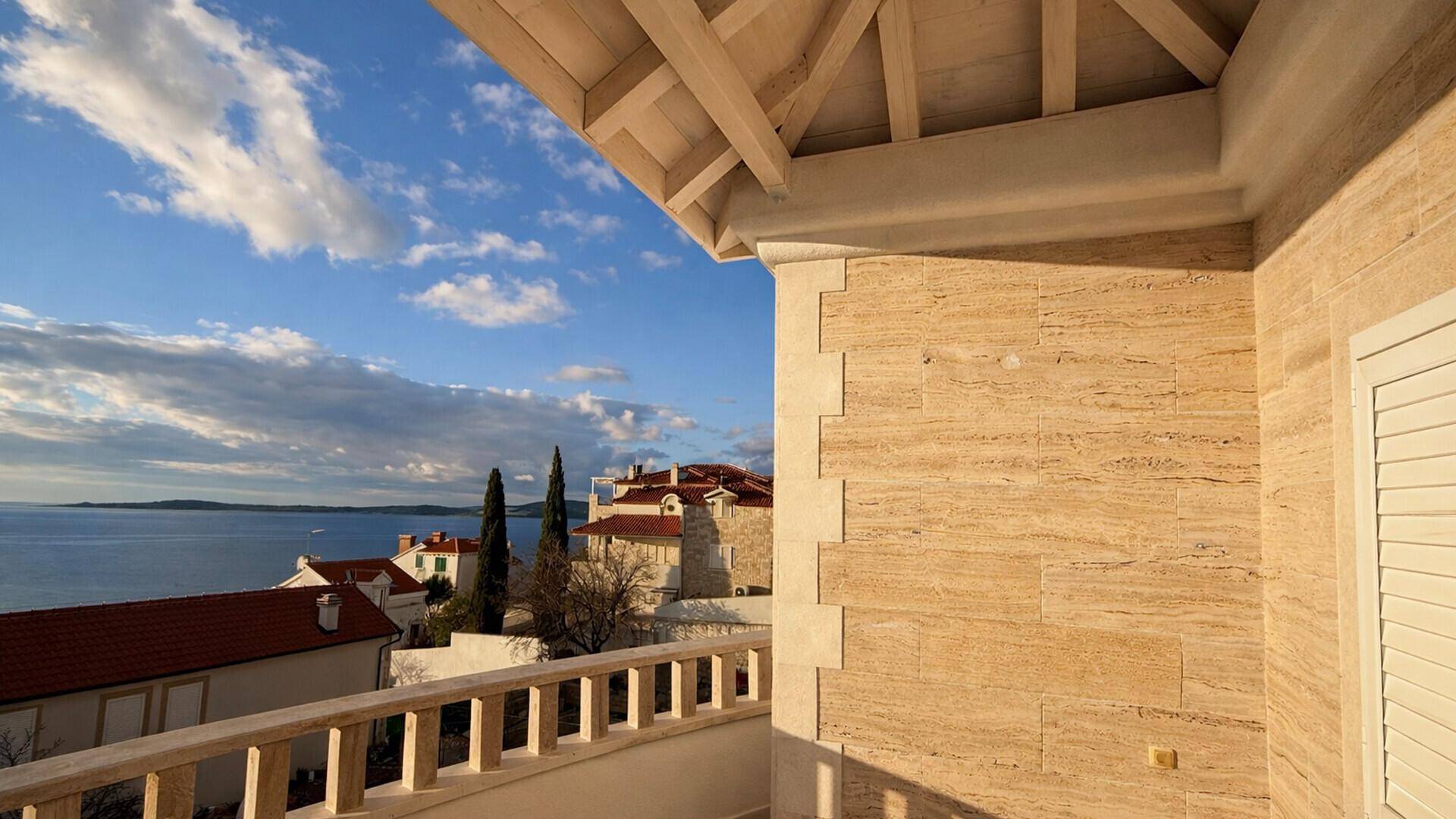 Balkon mit Holzdach und Steinverkleidung, bietet einen weiten Blick auf das Meer und die Umgebung.