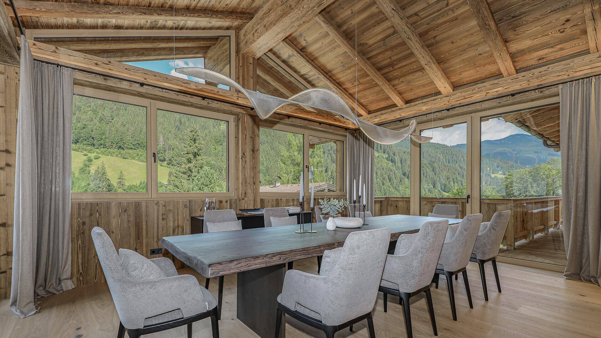 Geräumiger Essbereich mit langem Holztisch, Designerleuchte und weitem Blick auf die grüne Umgebung.