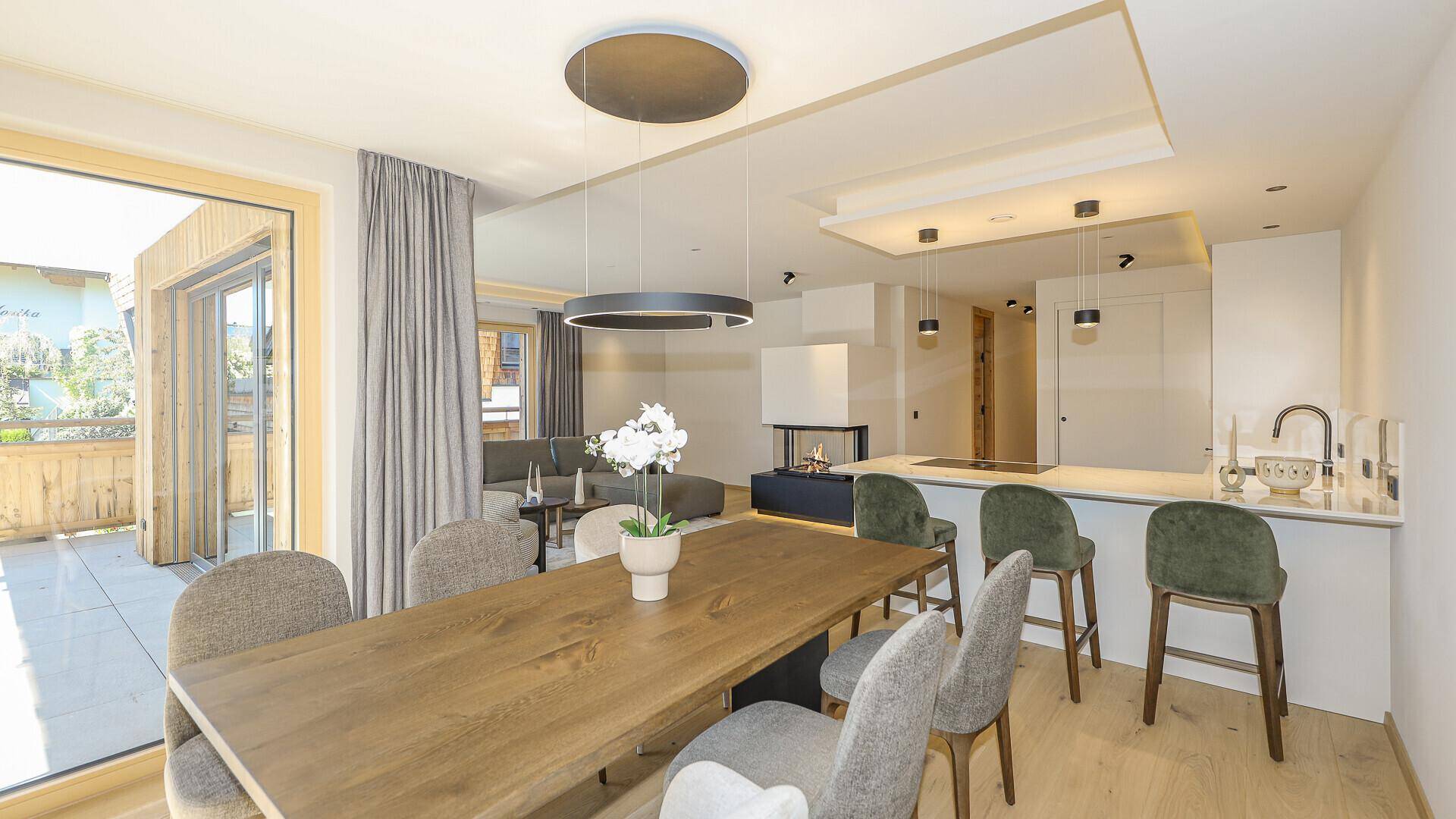 Eleganter Essbereich mit Holztisch, modernen Stühlen und Zugang zu einer sonnigen Terrasse.