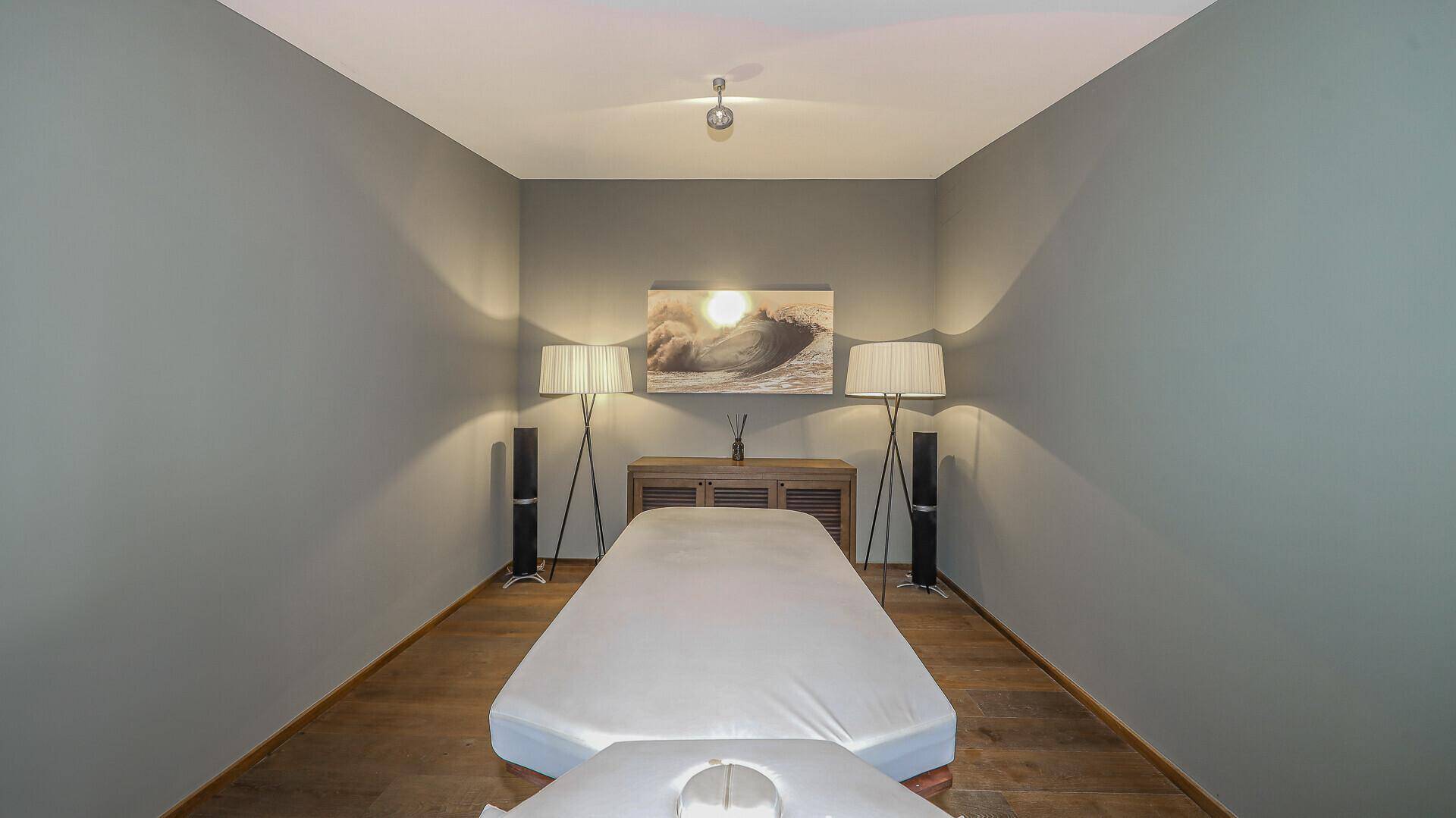 Ruhiger Raum mit Massageliege, gedämpfter Beleuchtung und minimalistischer Einrichtung.