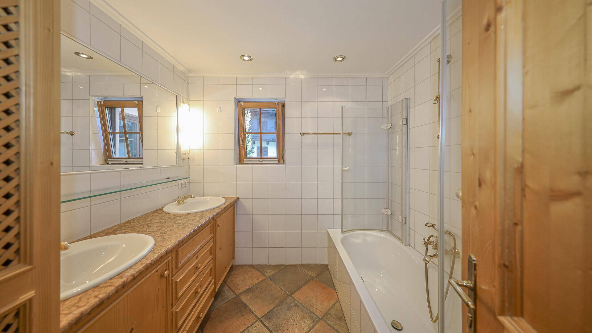 Helles Badezimmer mit Badewanne, Duschabtrennung und Doppelwaschbecken.
