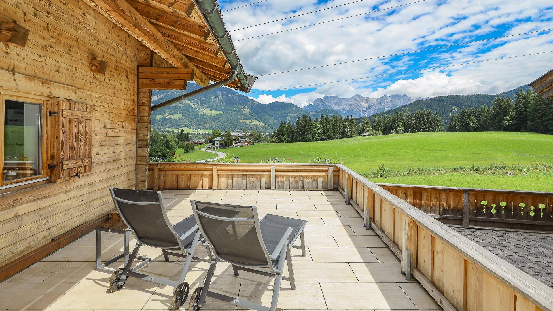 Geräumiger Balkon mit Sonnenliegen und atemberaubendem Panoramablick auf die Berge.