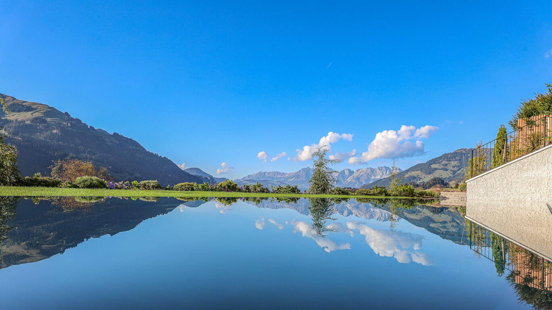Spiegelglatter Pool reflektiert den blauen Himmel und die majestätische Bergkulisse.