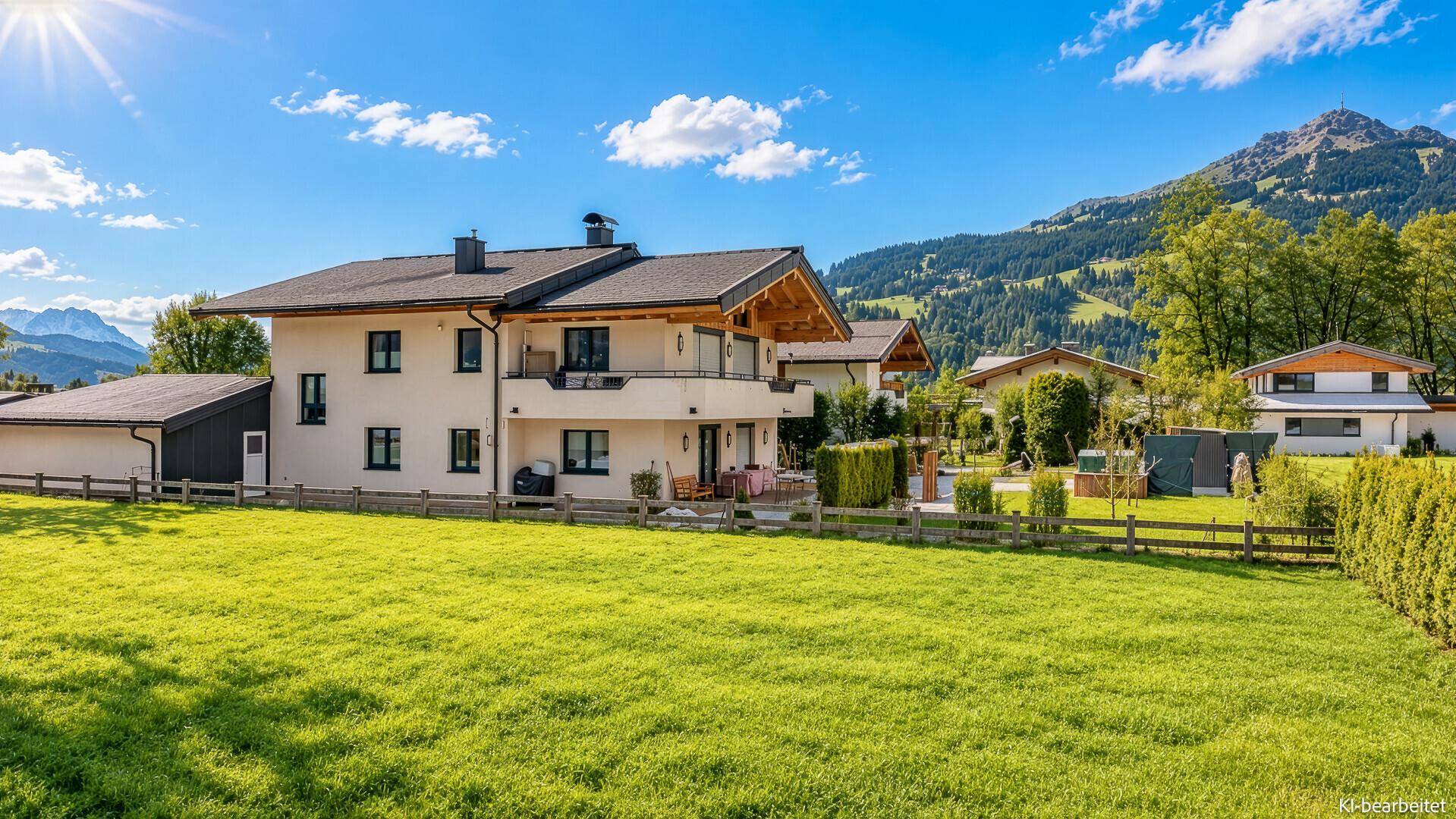 Großzügiger Garten mit weitem Rasen und traditionellem Haus vor der malerischen Berglandschaft.