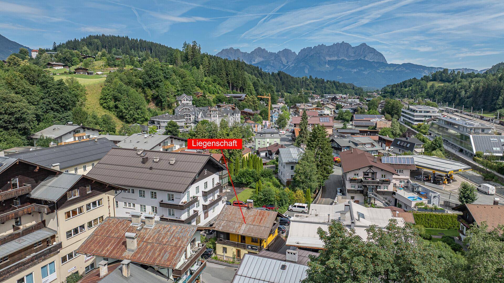 Weitläufige Ansicht der Stadt mit markiertem Objekt und beeindruckendem Bergpanorama.