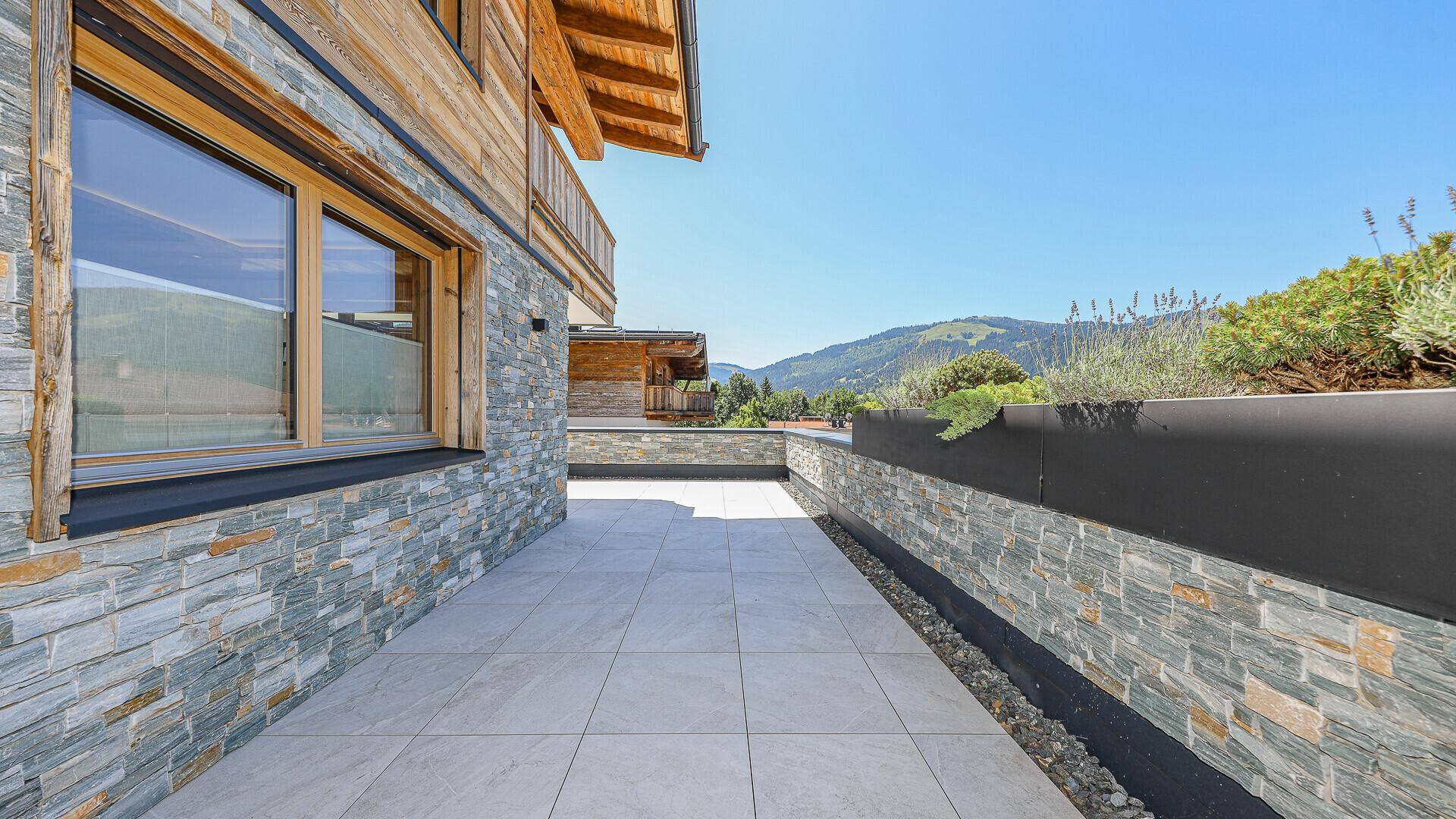 Geräumige, gepflasterte Terrasse mit Steinmauern und weitem Blick auf die Berge.