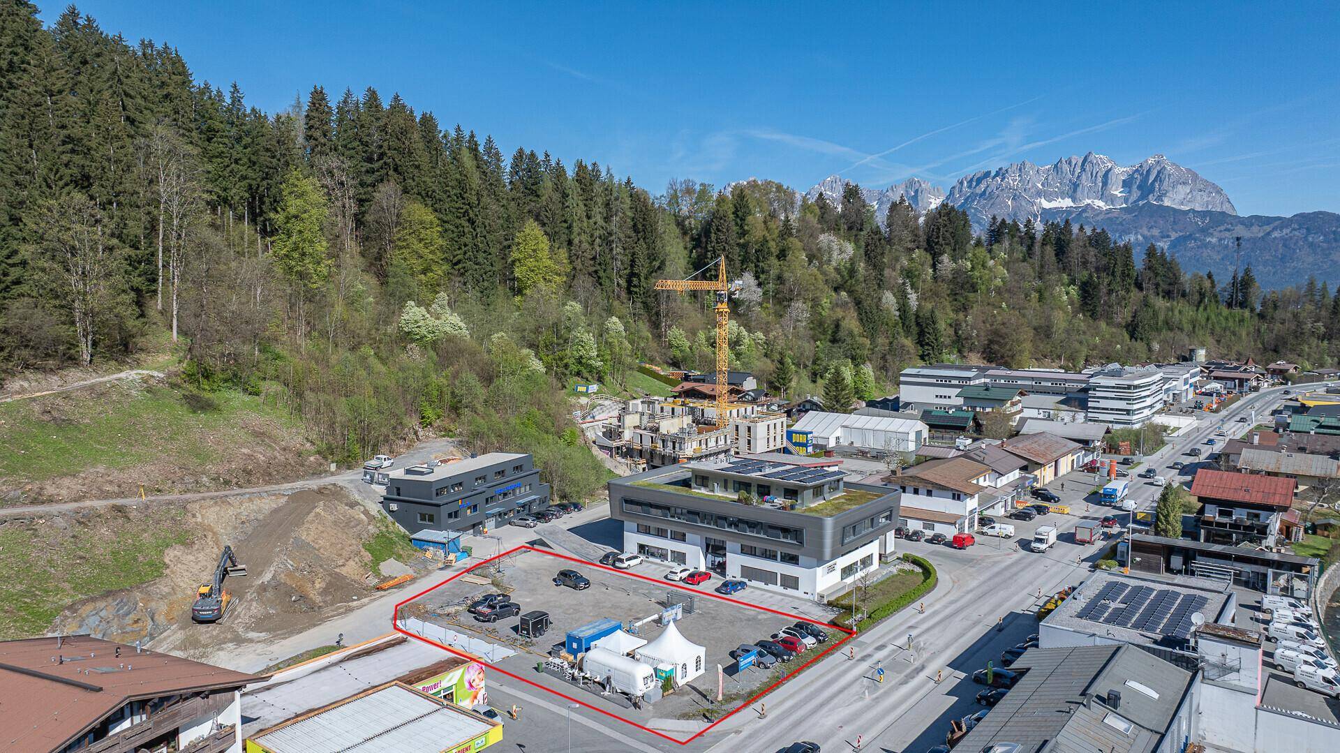 Nähere Luftaufnahme des Grundstücks mit umliegenden Gebäuden und einer Baustelle im Hintergrund.
