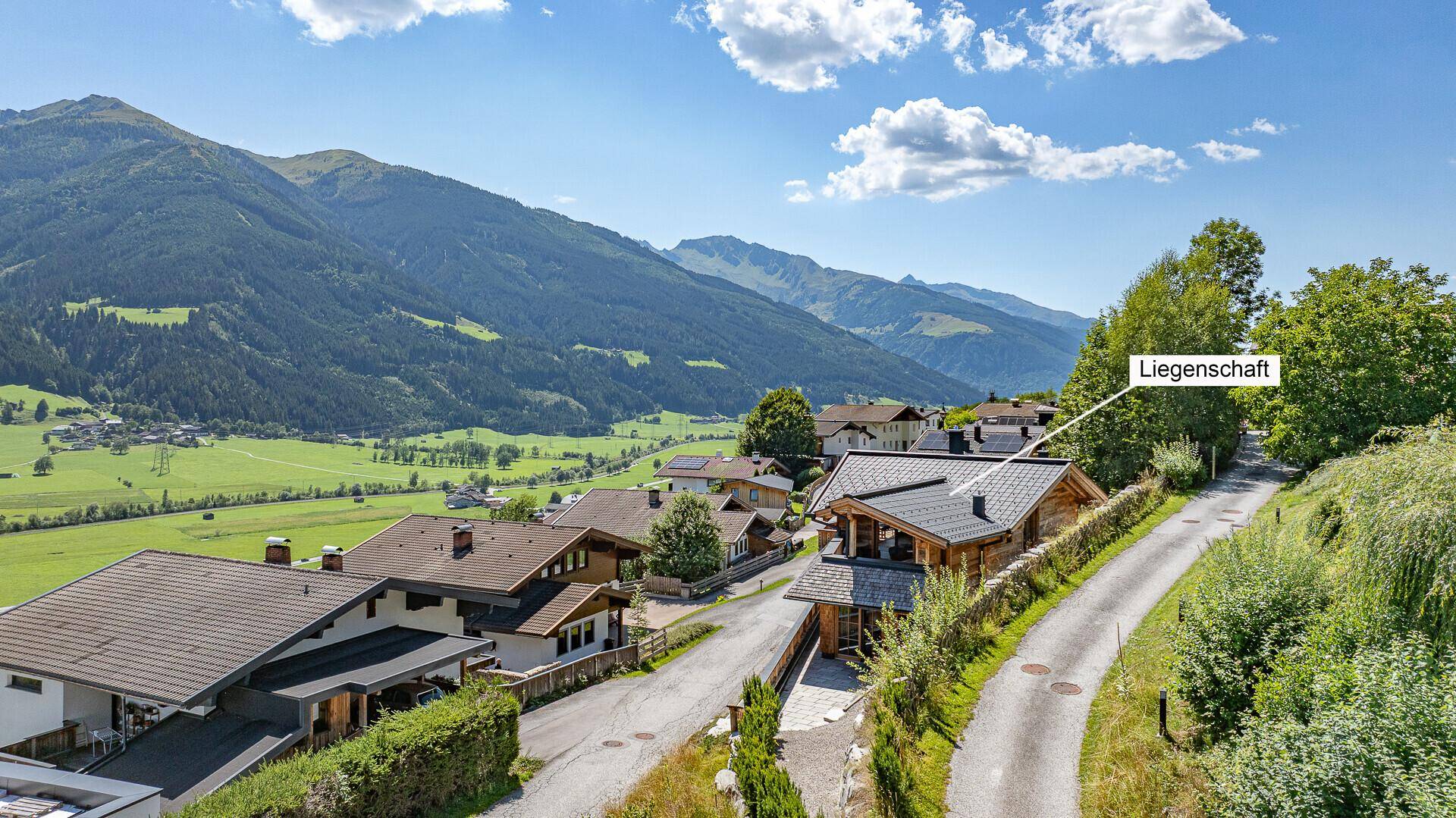 Luftaufnahme der Liegenschaft in einer idyllischen Bergregion mit umliegenden Häusern.