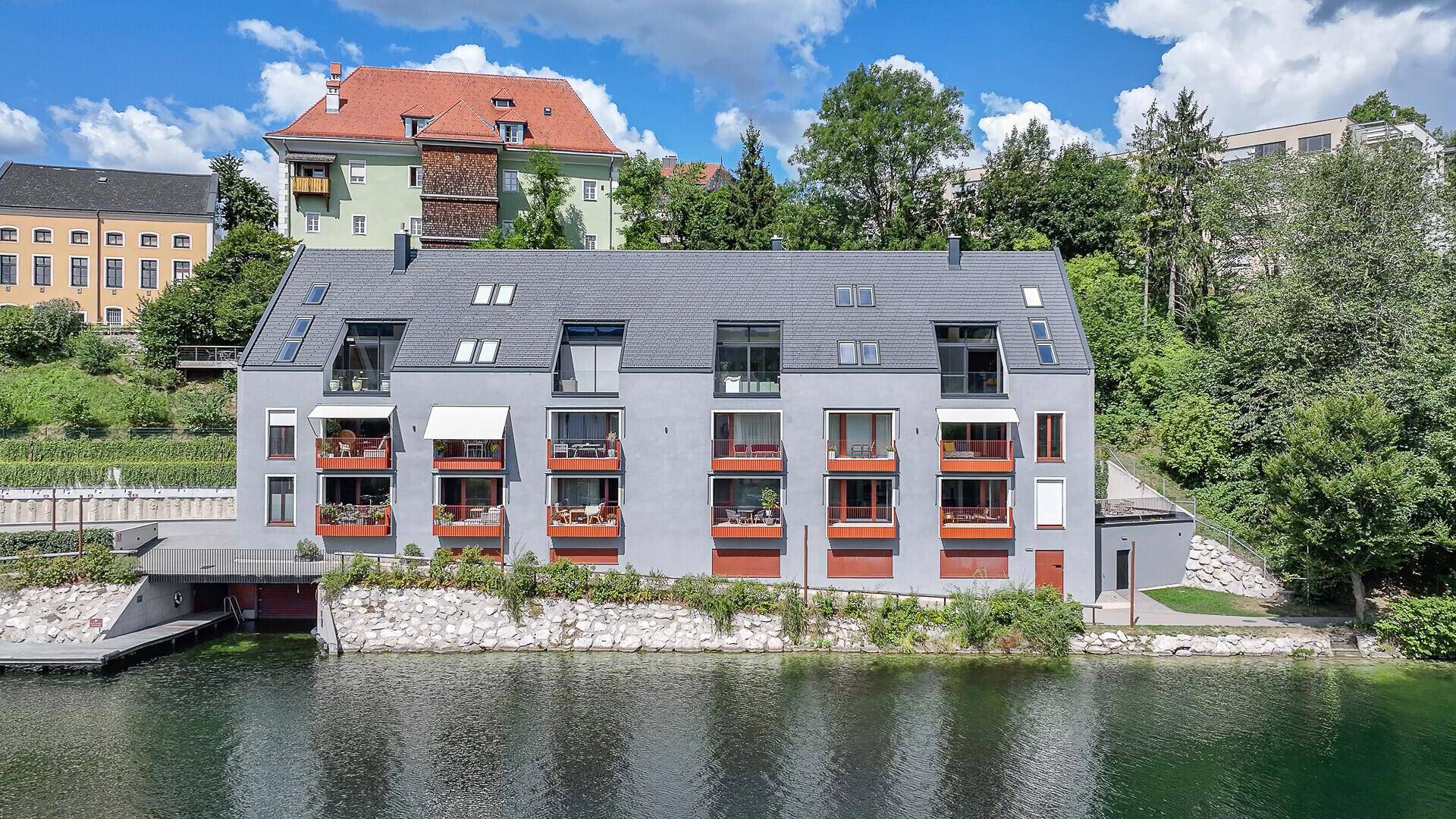Frontansicht des modernen Gebäudes am Wasser mit Balkonen und privatem Bootszugang.