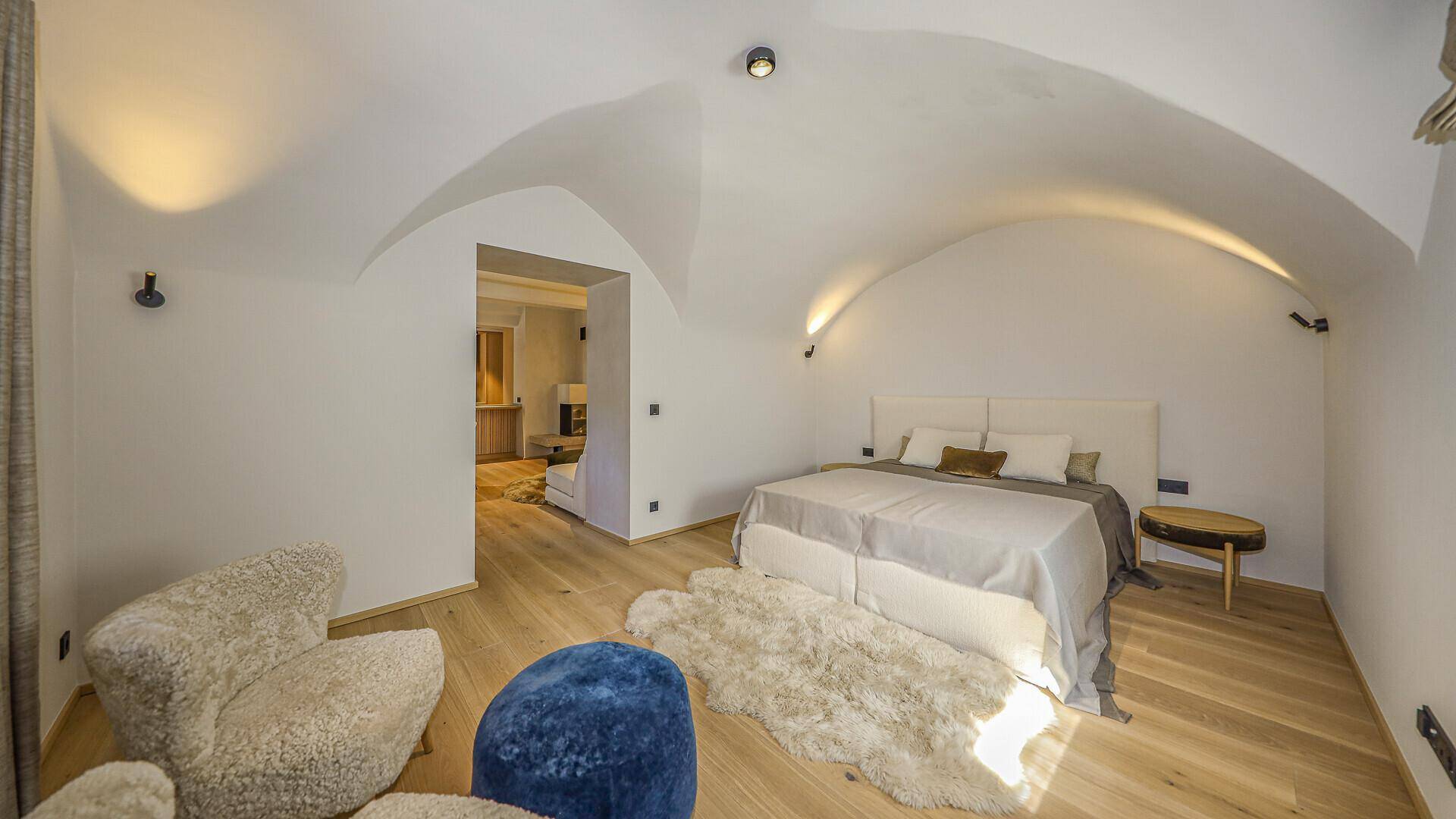 Großzügiges Schlafzimmer mit gewölbter Decke, Holzboden und Blick in den Flur.