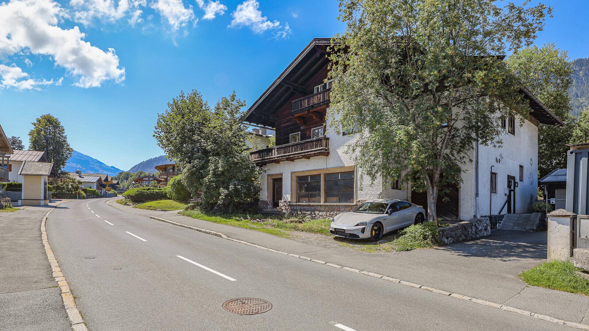 Traditionelles Haus mit Holzbalkonen und weißer Fassade an einer ruhigen Straße.