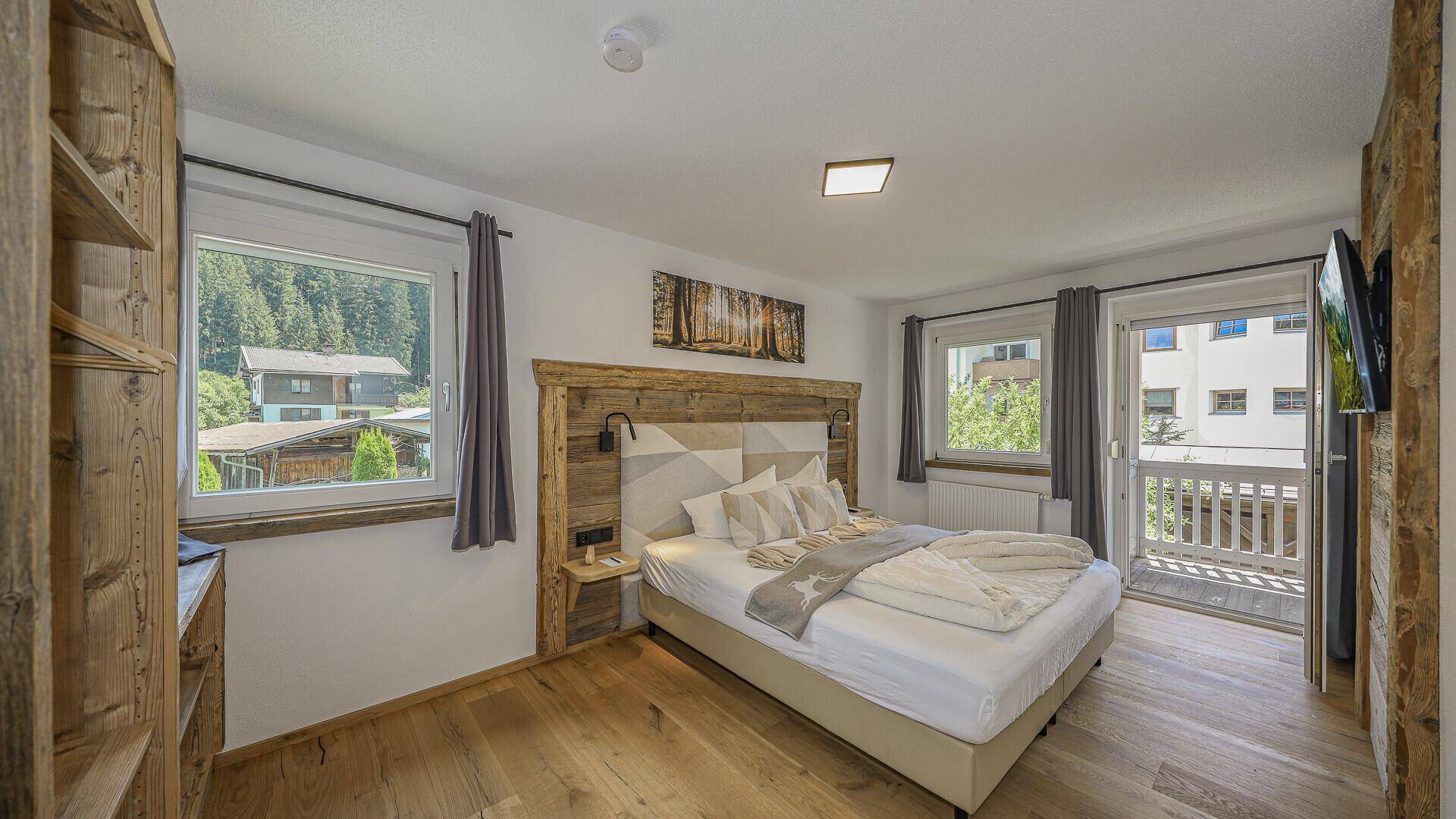 Helles Schlafzimmer mit Holzboden, Doppelbett und direktem Zugang zu einem kleinen Balkon.