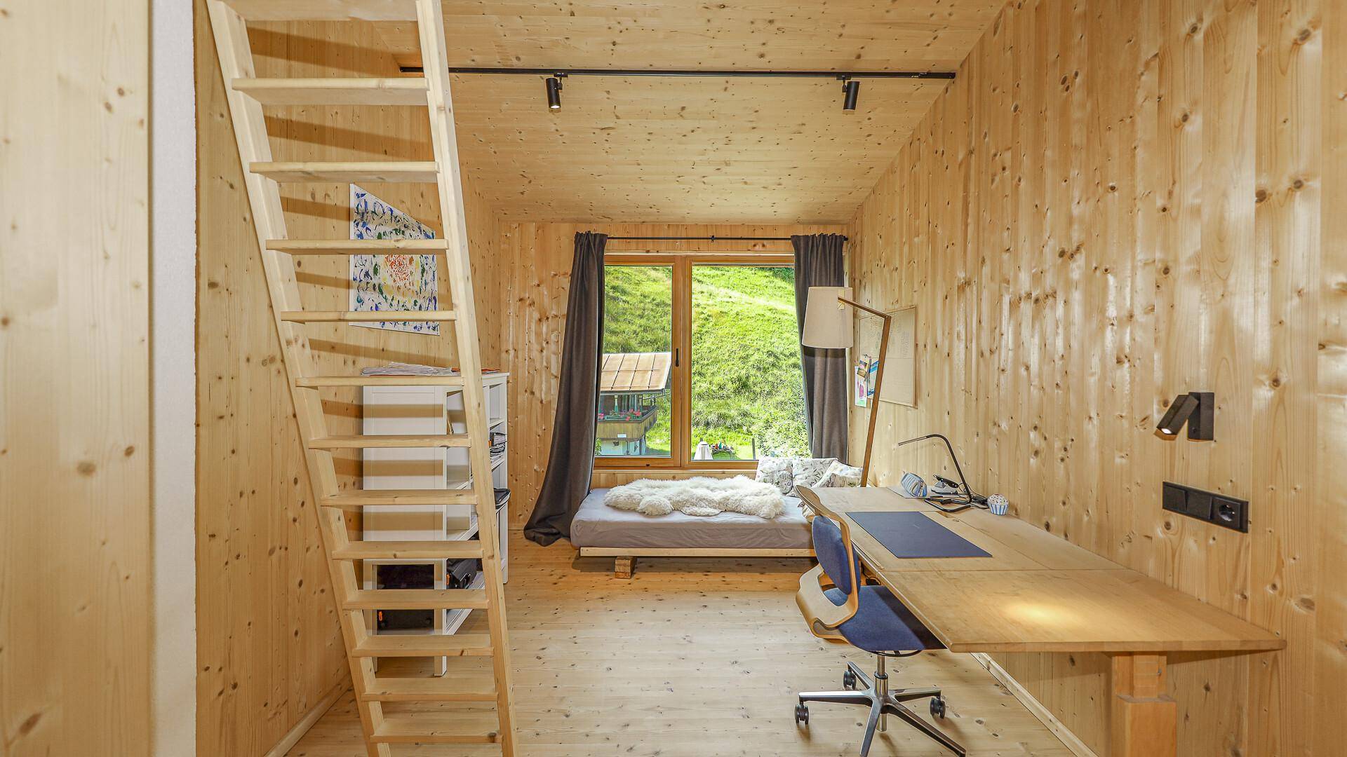 Helles Zimmer mit Holzwänden, Schreibtisch und Blick ins Grüne, ideal als Büro oder Kinderzimmer.