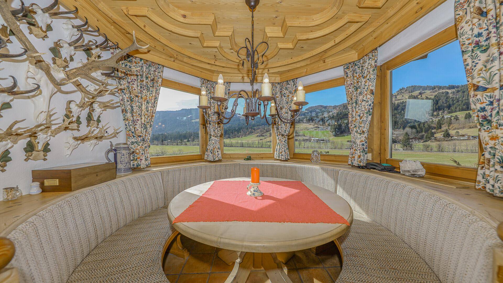 Gemütlicher Essbereich mit runder Sitzbank, Holztisch und Panoramablick auf die Landschaft.