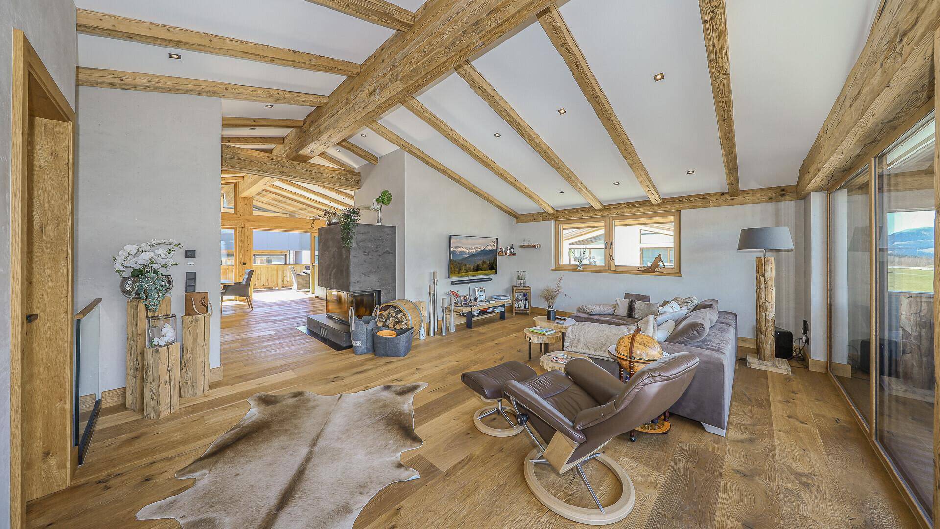 Lichtdurchfluteter Wohnbereich mit Kamin, Holzbalken und Zugang zur Terrasse.