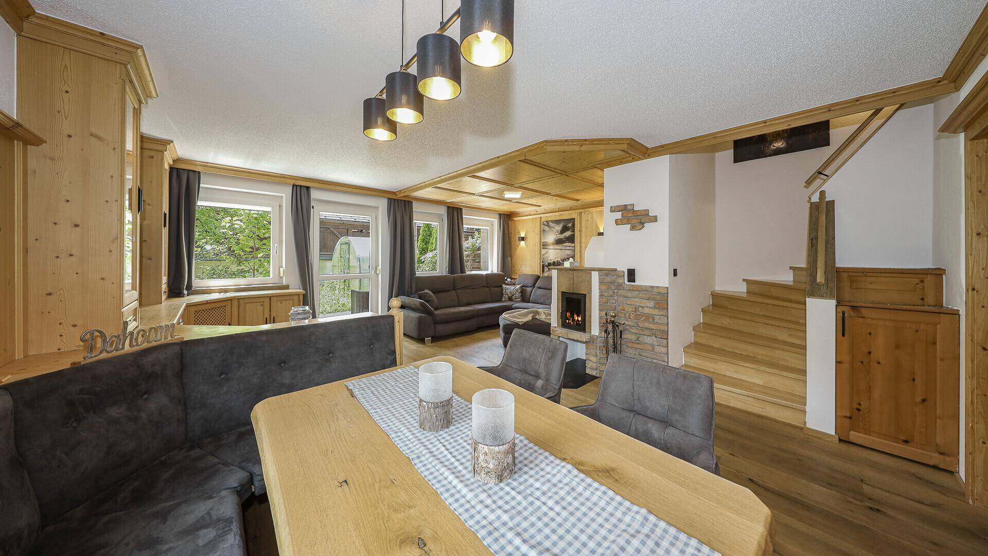 Offener Wohn- und Essbereich mit Holzboden, Kamin und traditioneller Einrichtung im alpinen Stil.