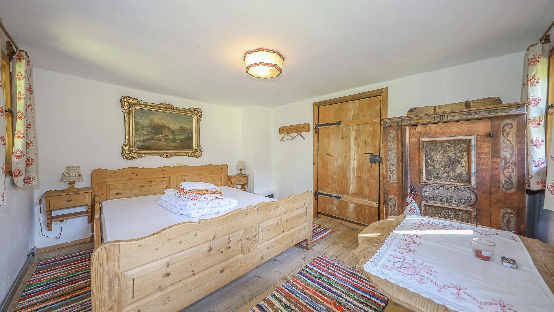 Gemütliches Schlafzimmer mit traditionellem Holzbett, bemaltem Schrank und rustikalem Charme.