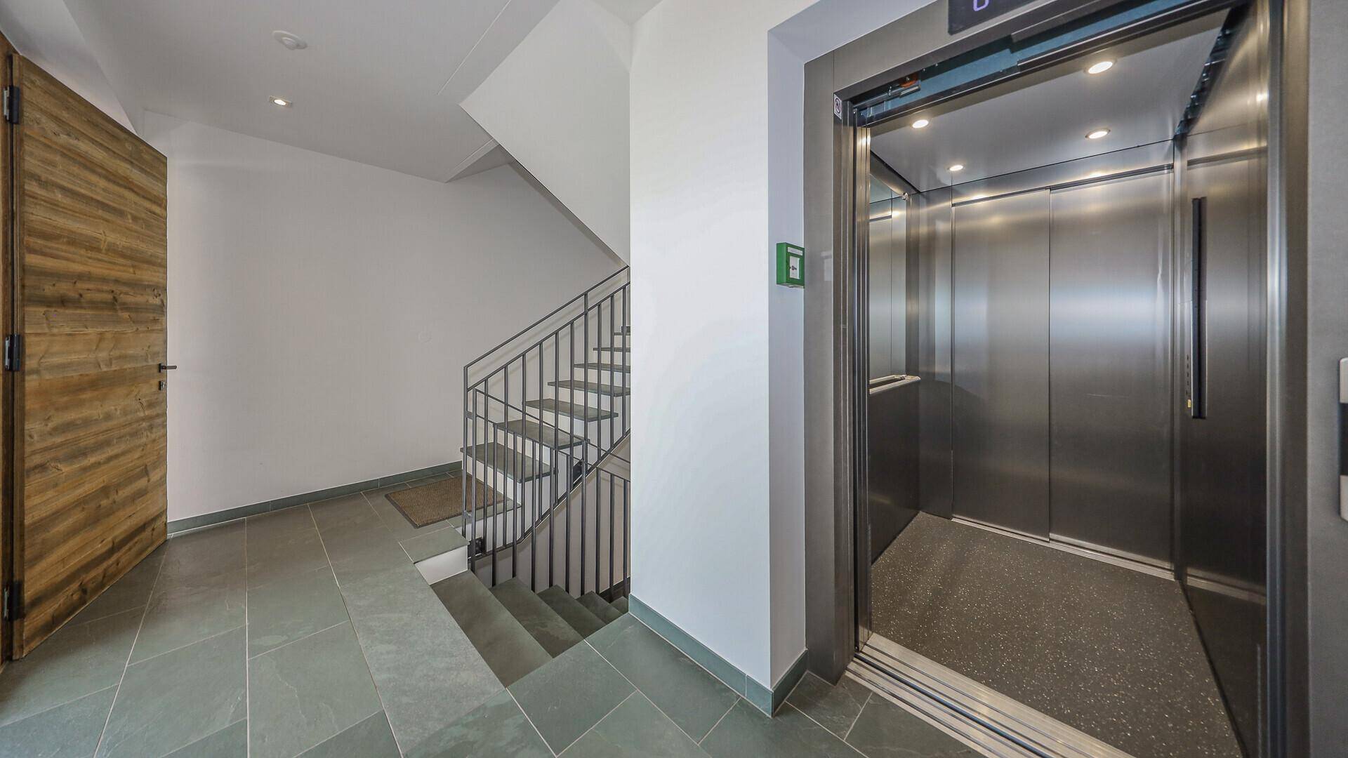 Treppenhaus und moderner Aufzug in einem gemeinschaftlichen Eingangsbereich.