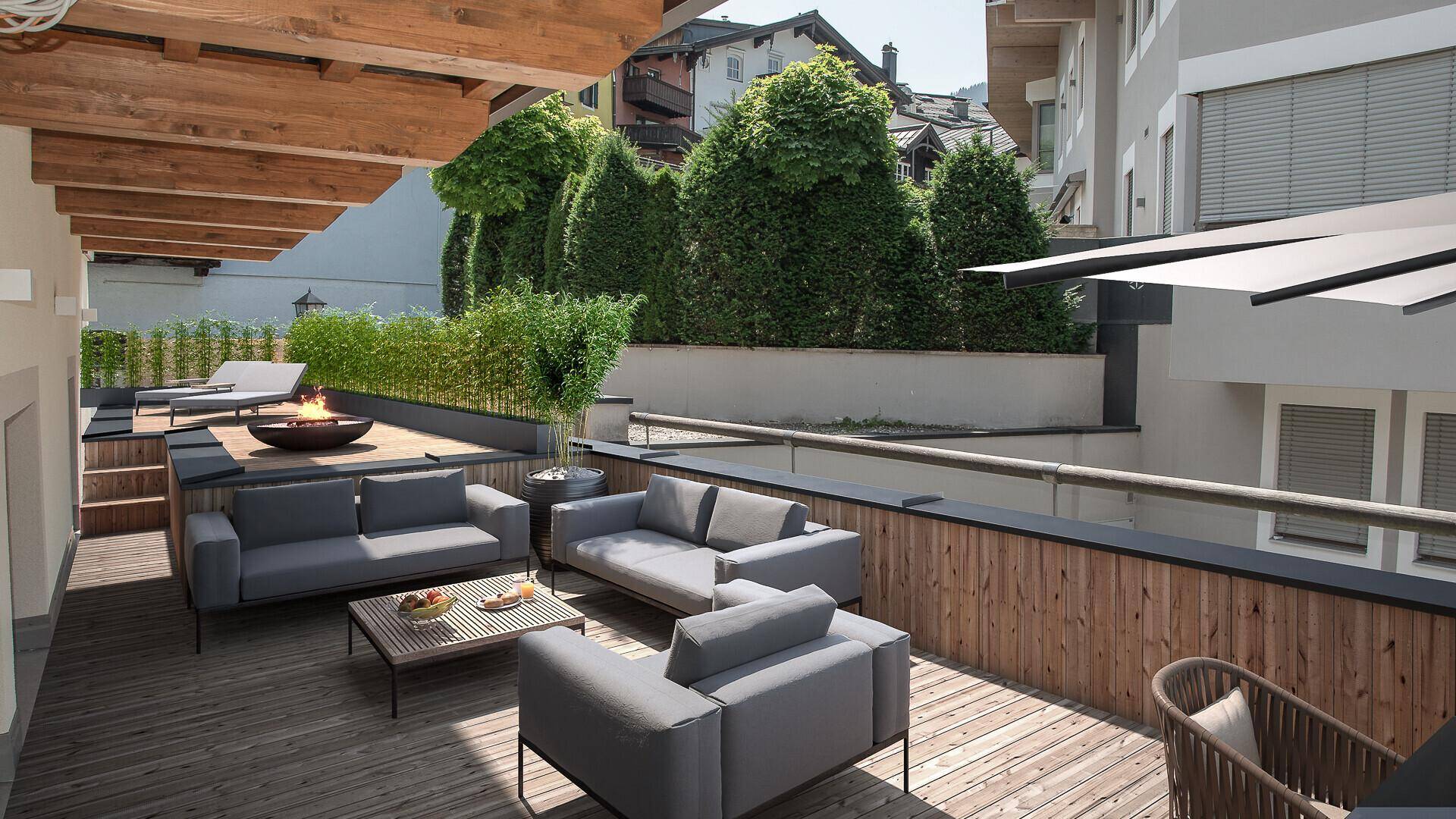 Moderne Dachterrasse mit bequemen Loungemöbeln, Feuerstelle und Holzboden, umgeben von grünen Pflanzen.