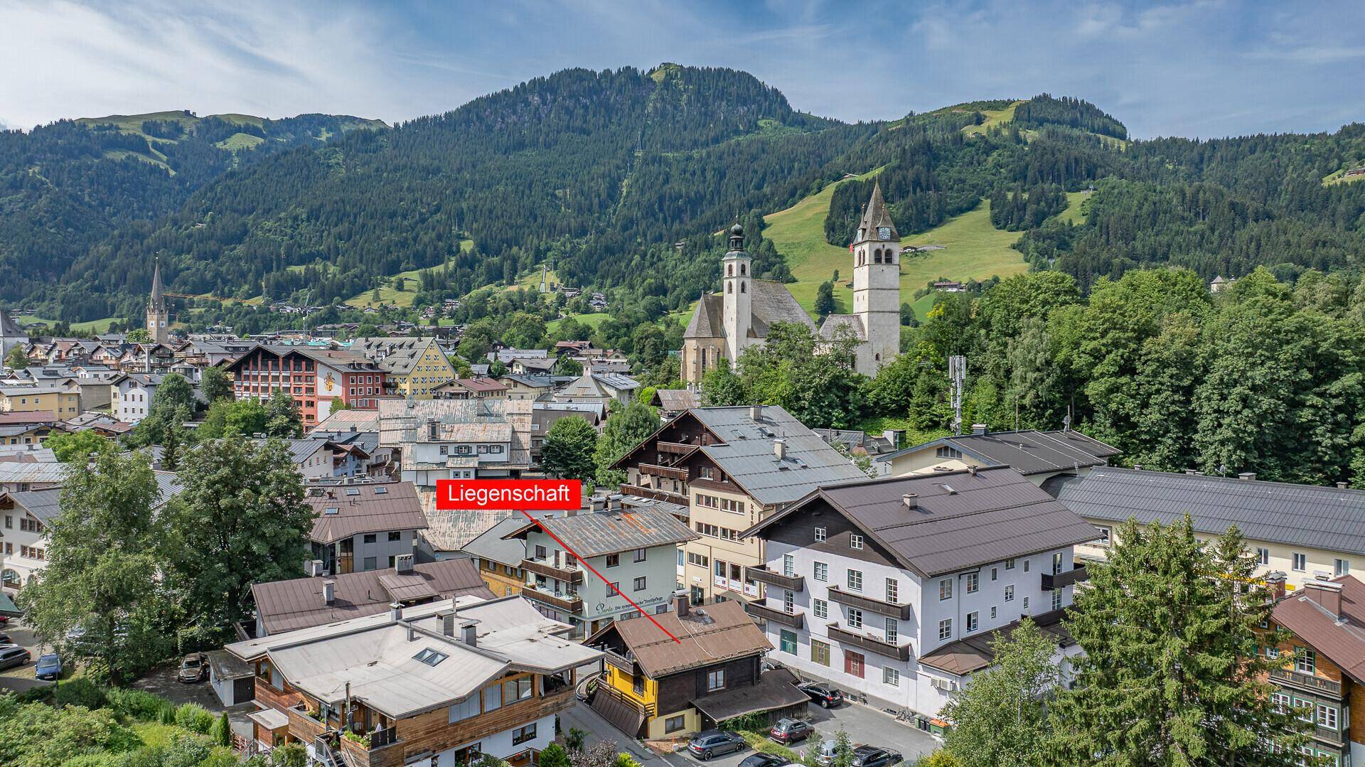 Luftaufnahme der Stadt mit markierter Liegenschaft und umliegender Berglandschaft.