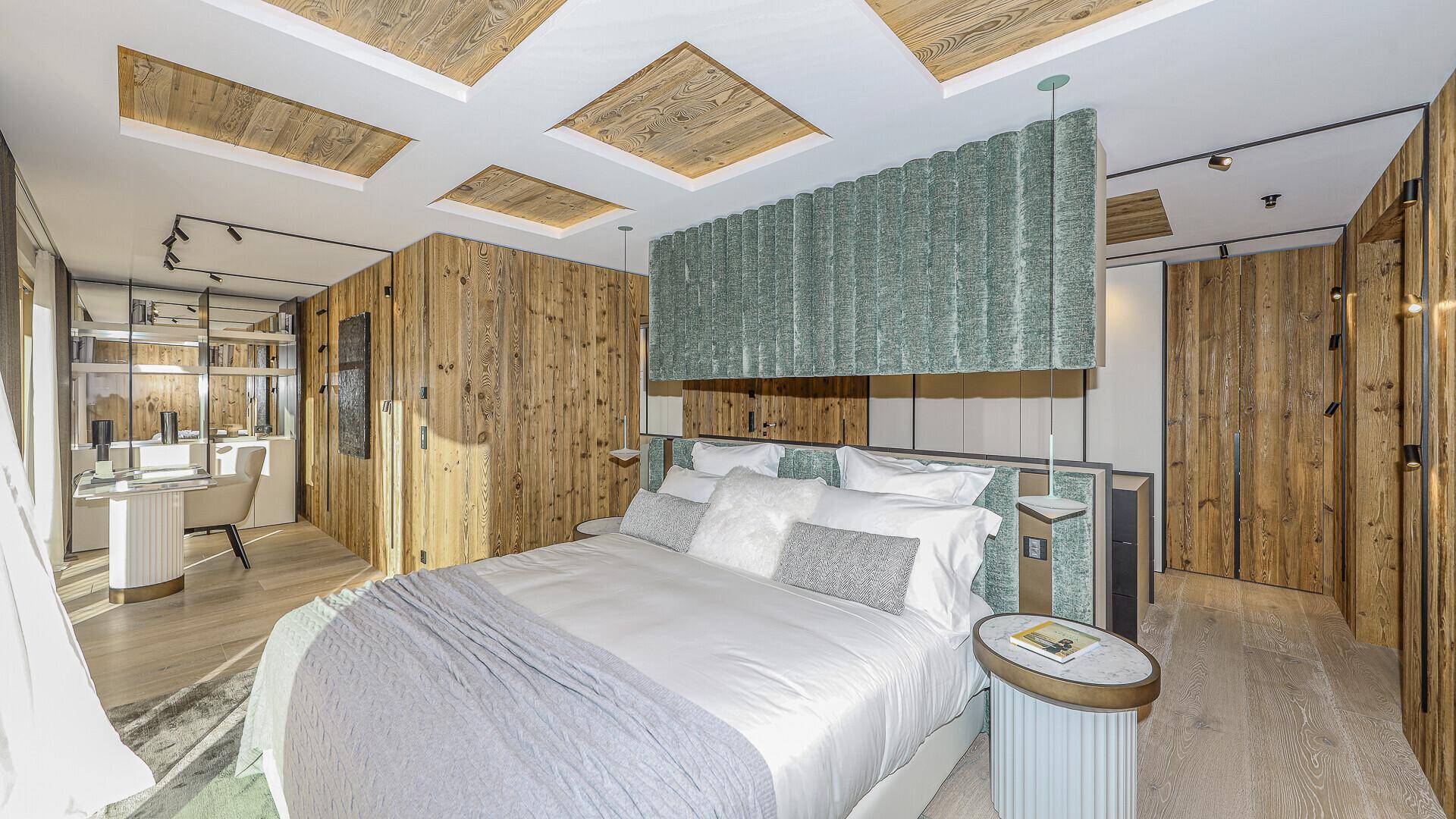 Elegantes Schlafzimmer mit Holzwänden, modernem Bett und integriertem Arbeitsbereich.