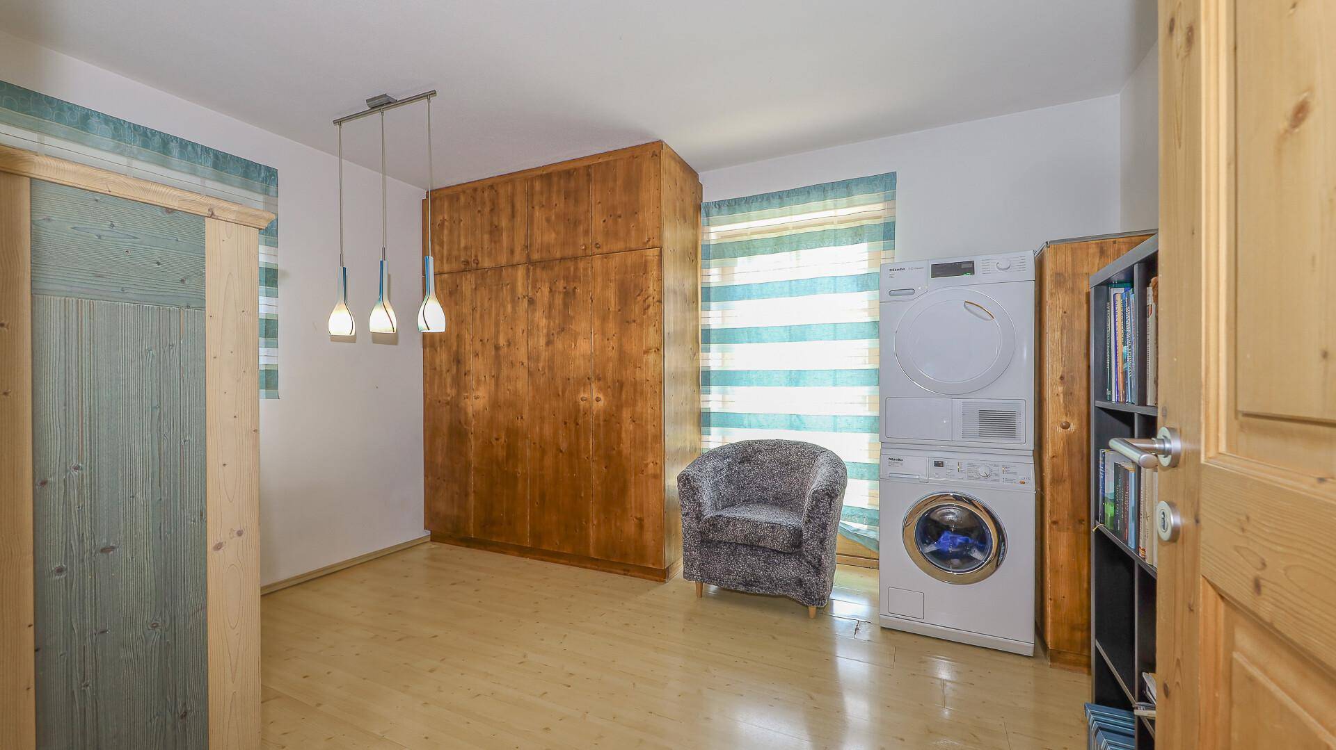 Hauswirtschaftsraum mit Waschmaschine, Trockner und praktischem Holzschrank.