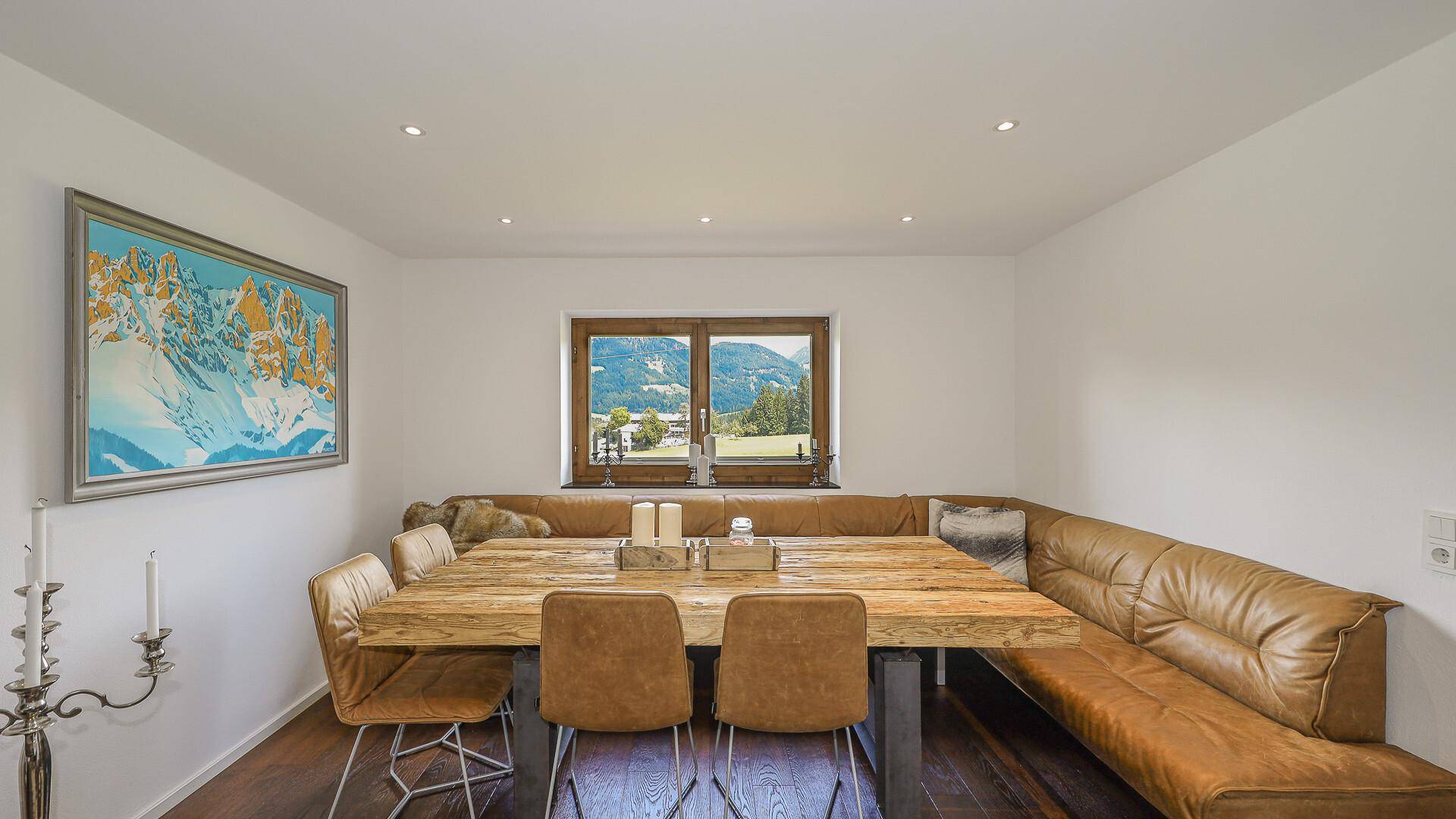 Gemütlicher Essbereich mit Holztisch, Eckbank und Bergblick durch das Fenster.