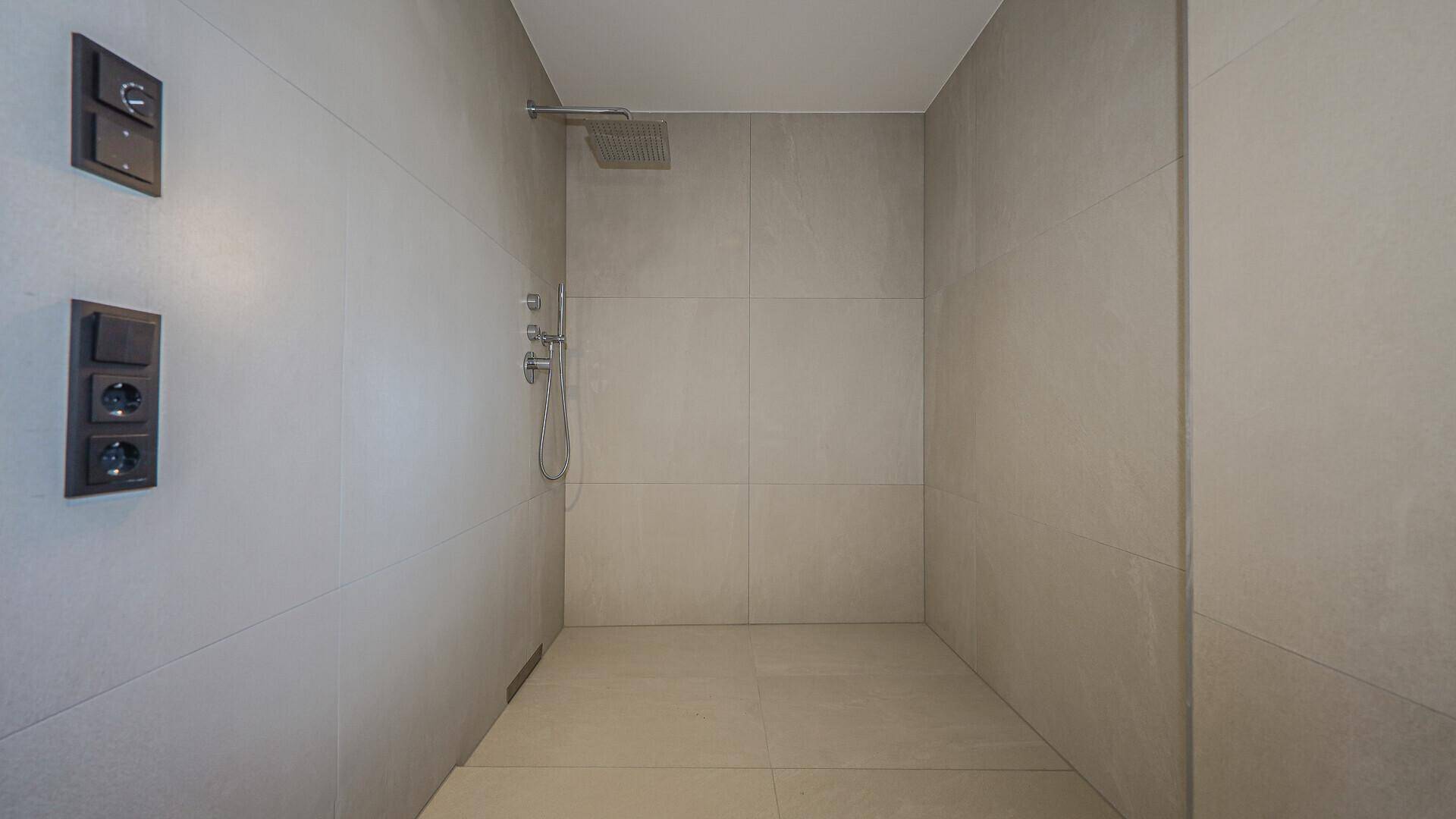 Modernes Badezimmer mit großformatigen Fliesen und einer geräumigen begehbaren Dusche.