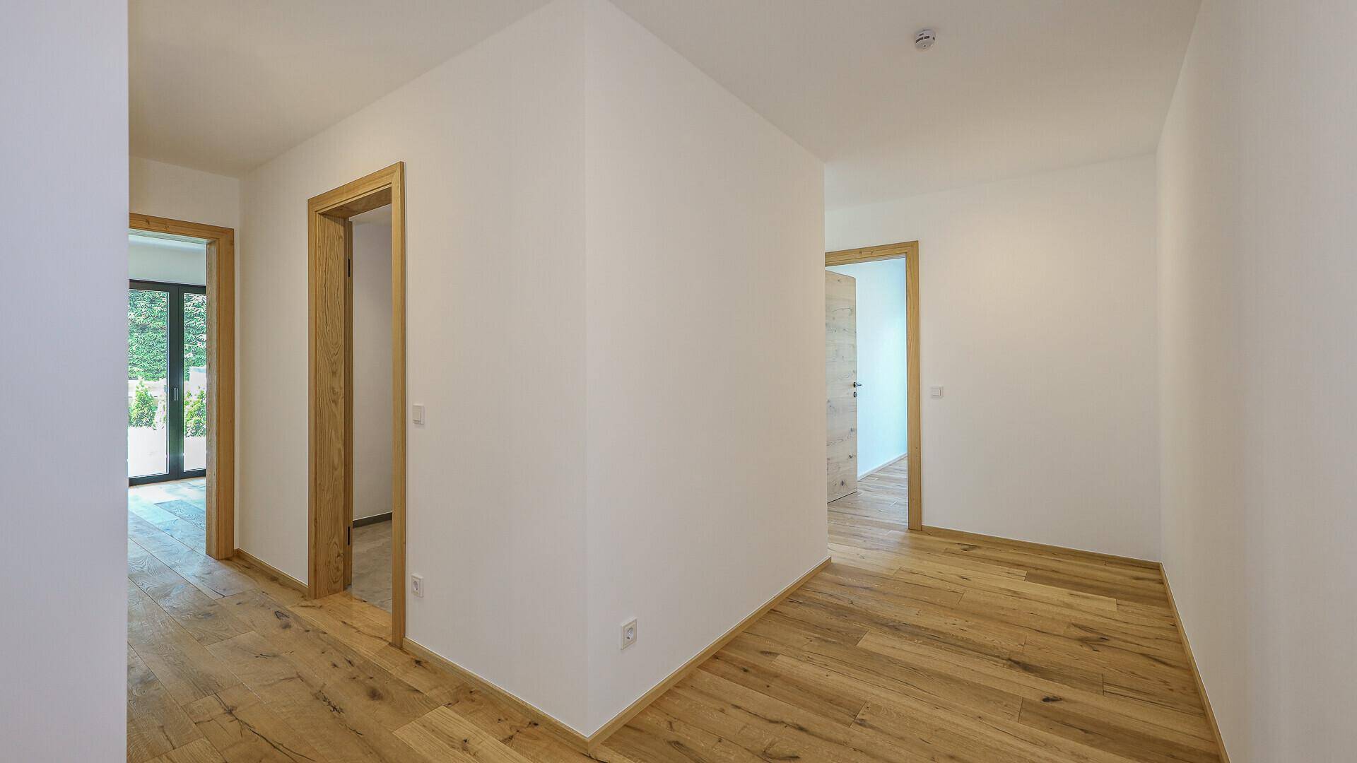 Heller Flur mit Holzboden und mehreren Türen, die zu anderen Räumen führen.
